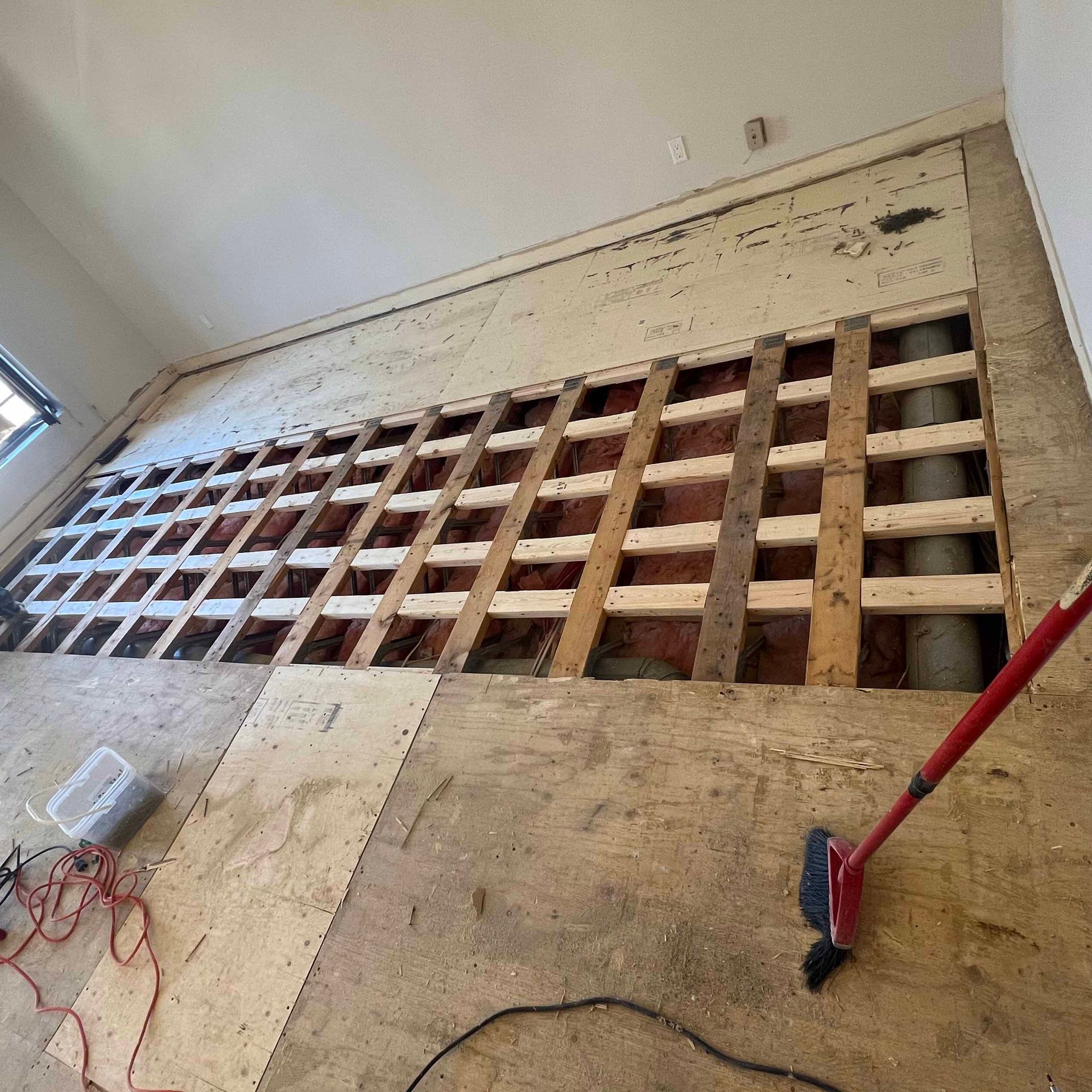 A room with a hole in the floor and a broom.