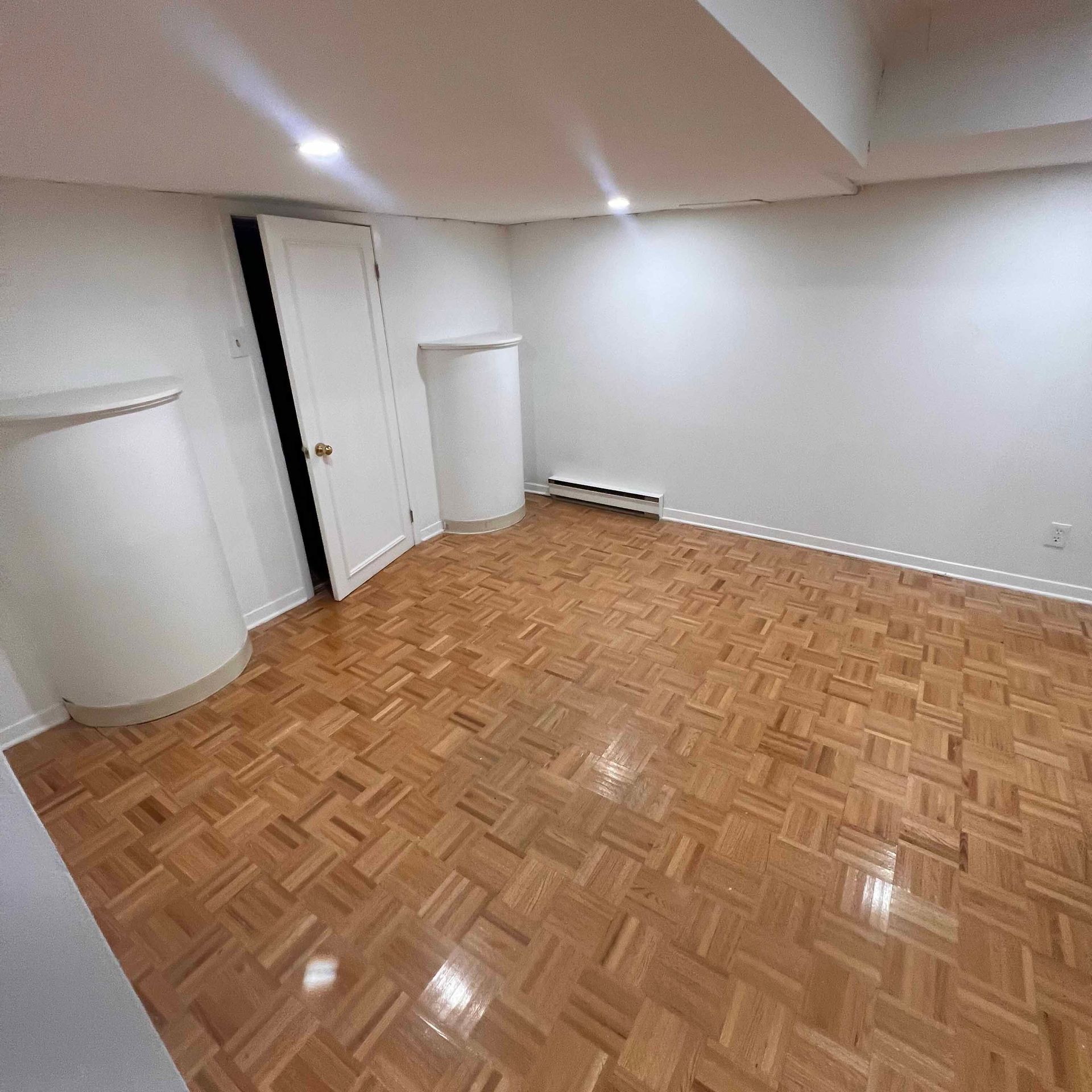 An empty room with a wooden floor and white walls.