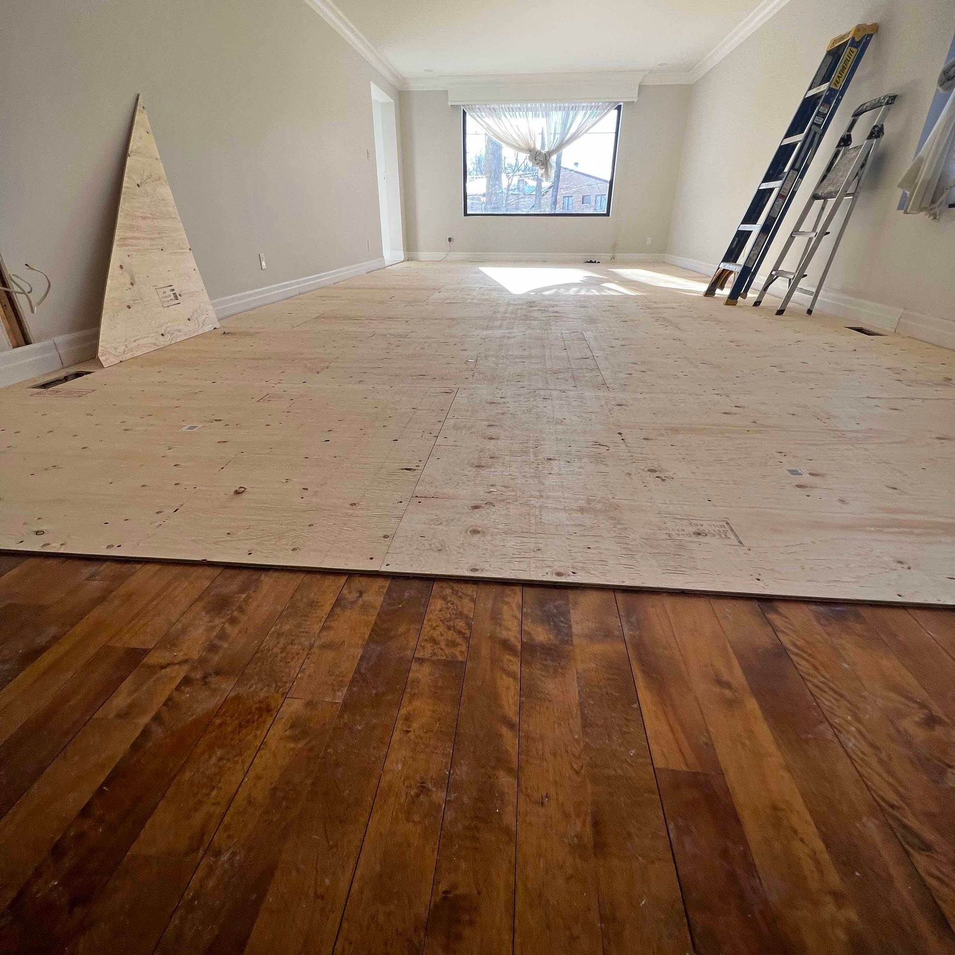 An empty room with a wooden floor and a ladder