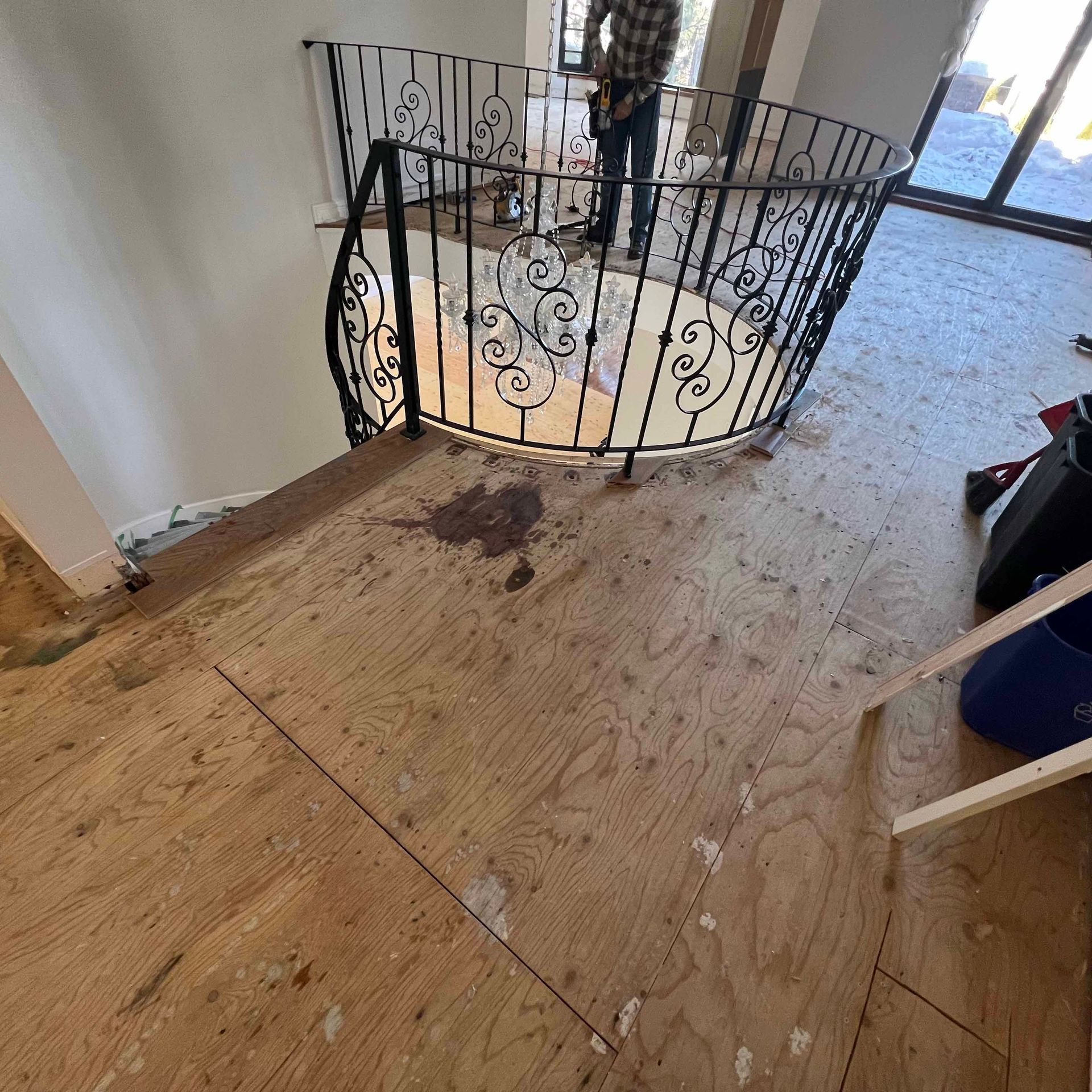 A man is standing on a spiral staircase with a wrought iron railing.