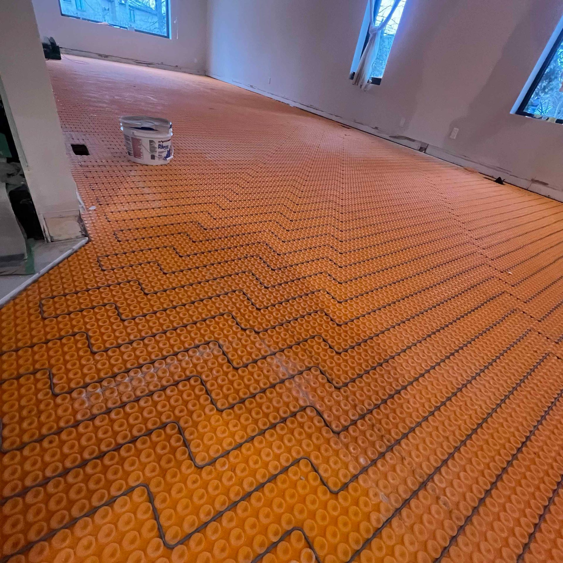 A large room with a carpeted floor and a bucket on the floor.