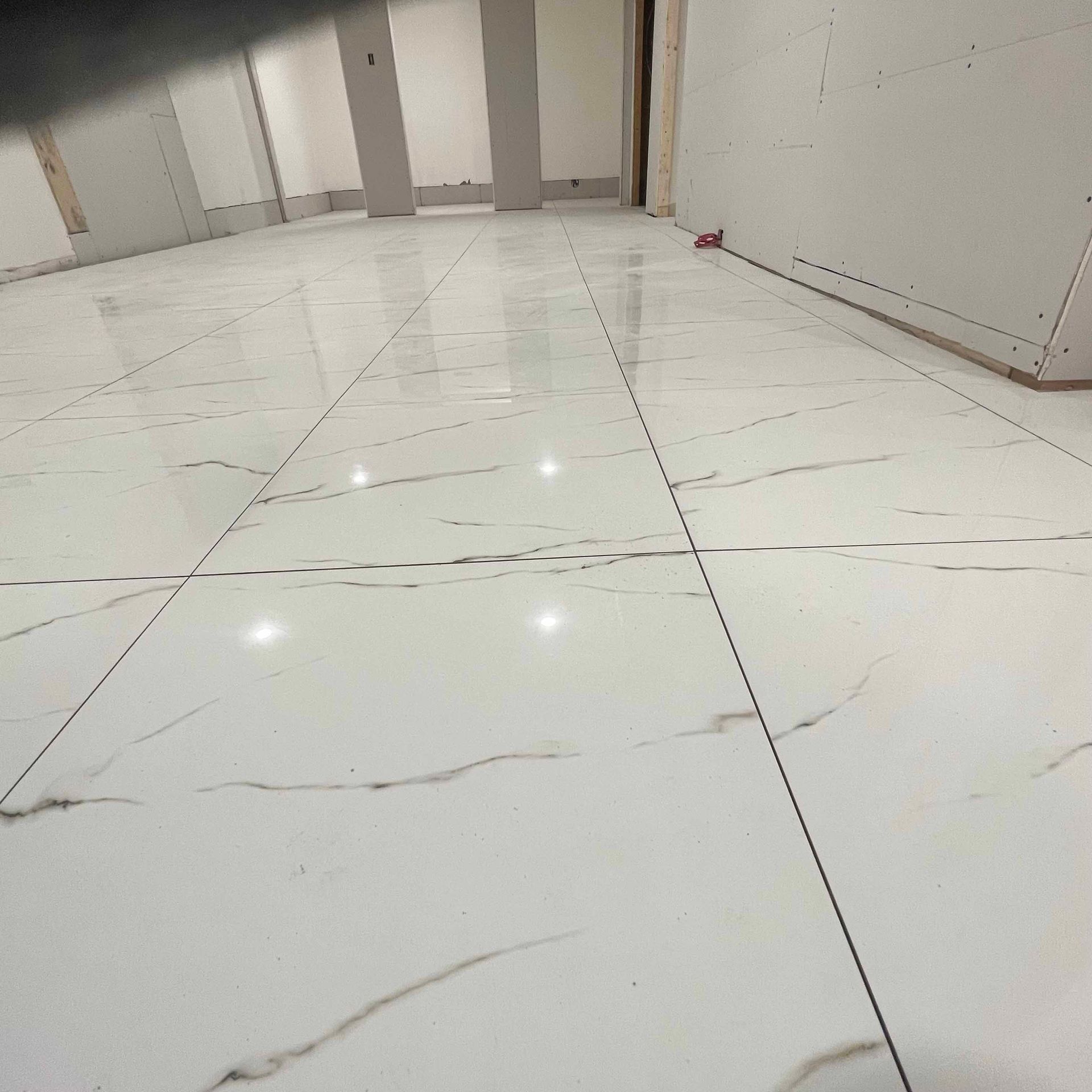 A white tiled floor in a room with a door.