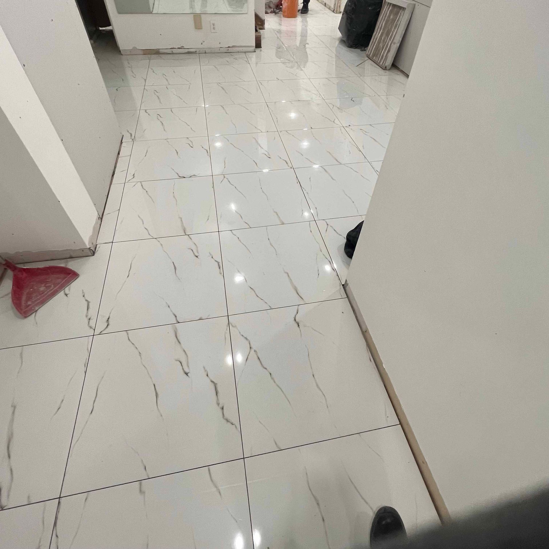 A person is standing on a tiled floor in a hallway.