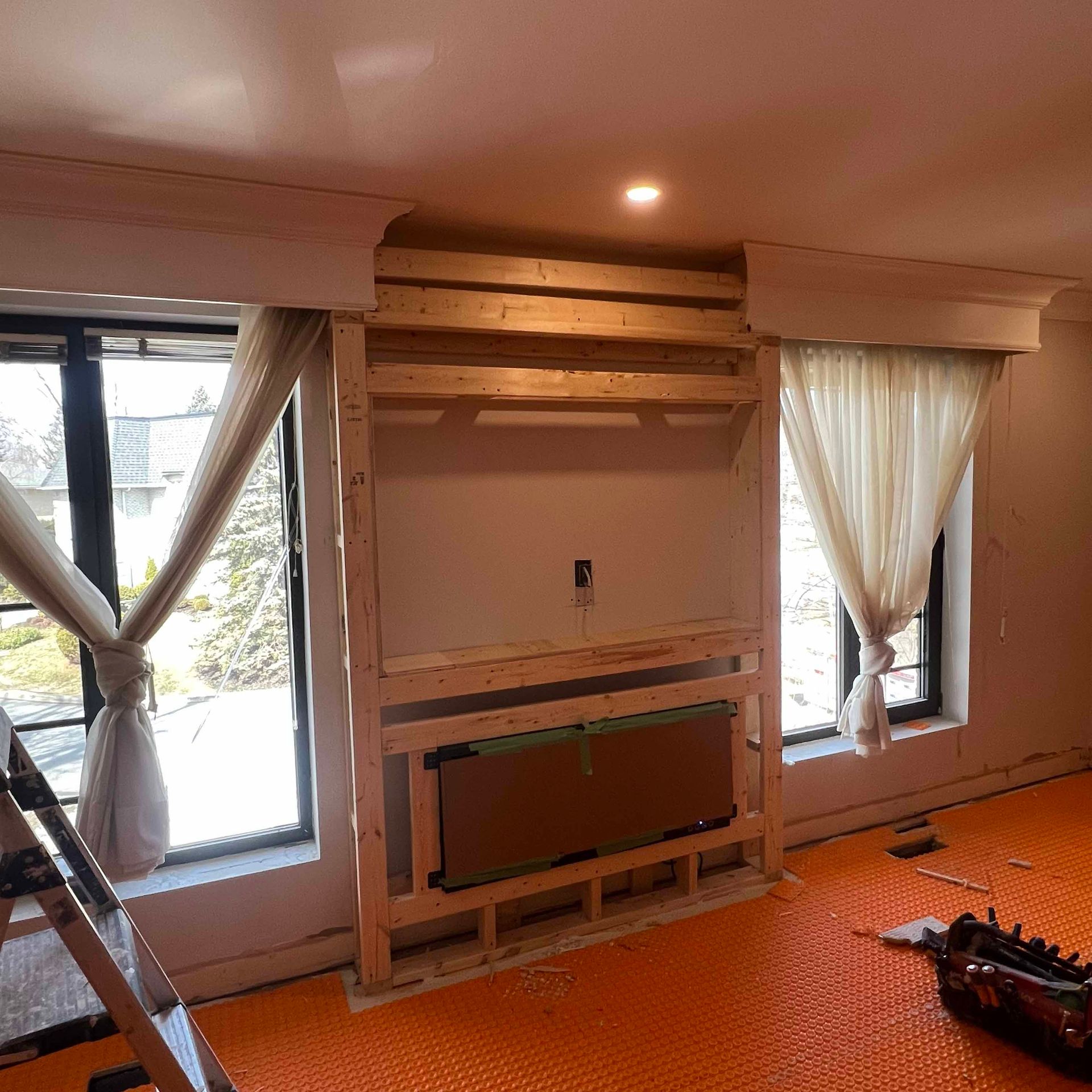 A living room with a wooden fireplace and a ladder.