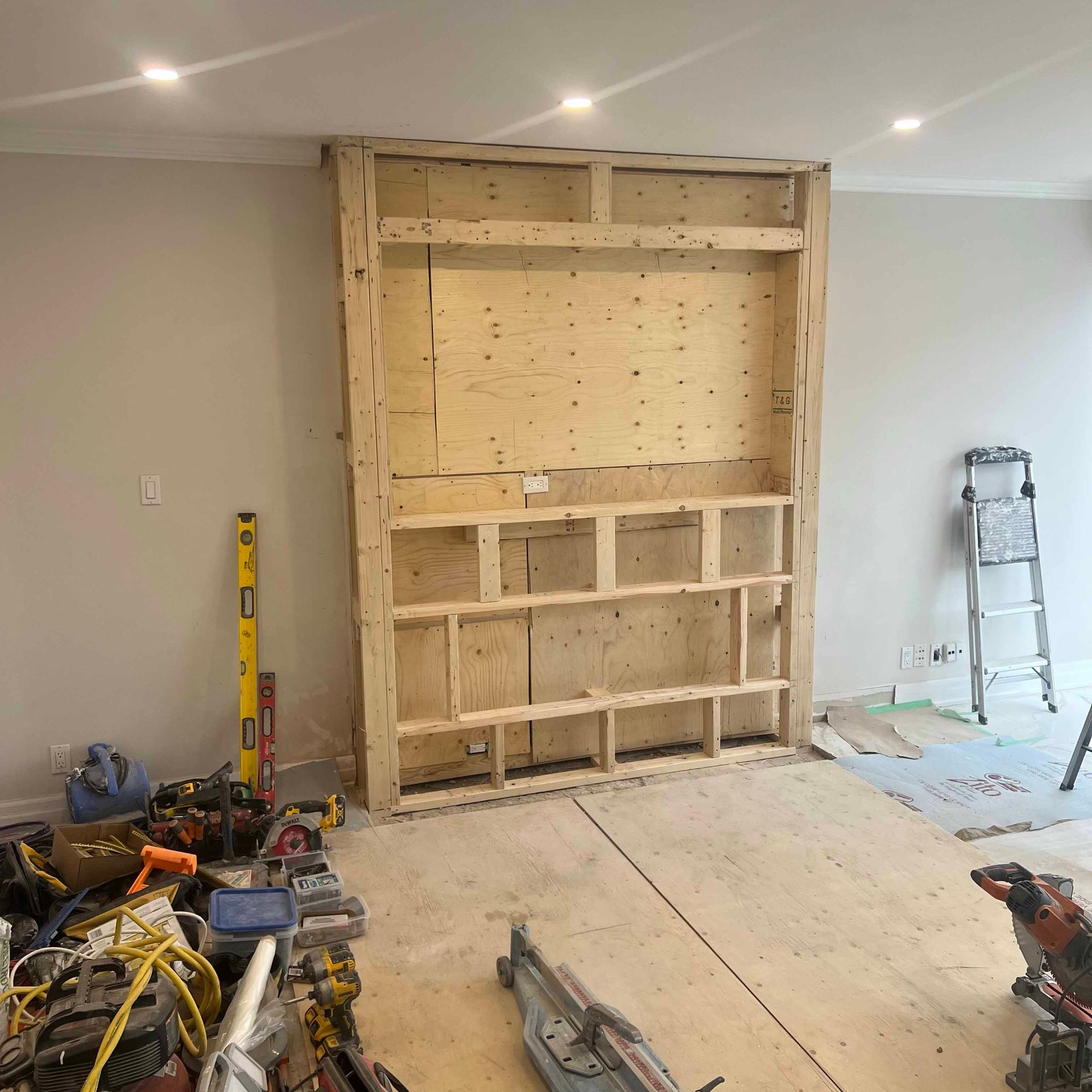 A large wooden shelf is being built in a room.