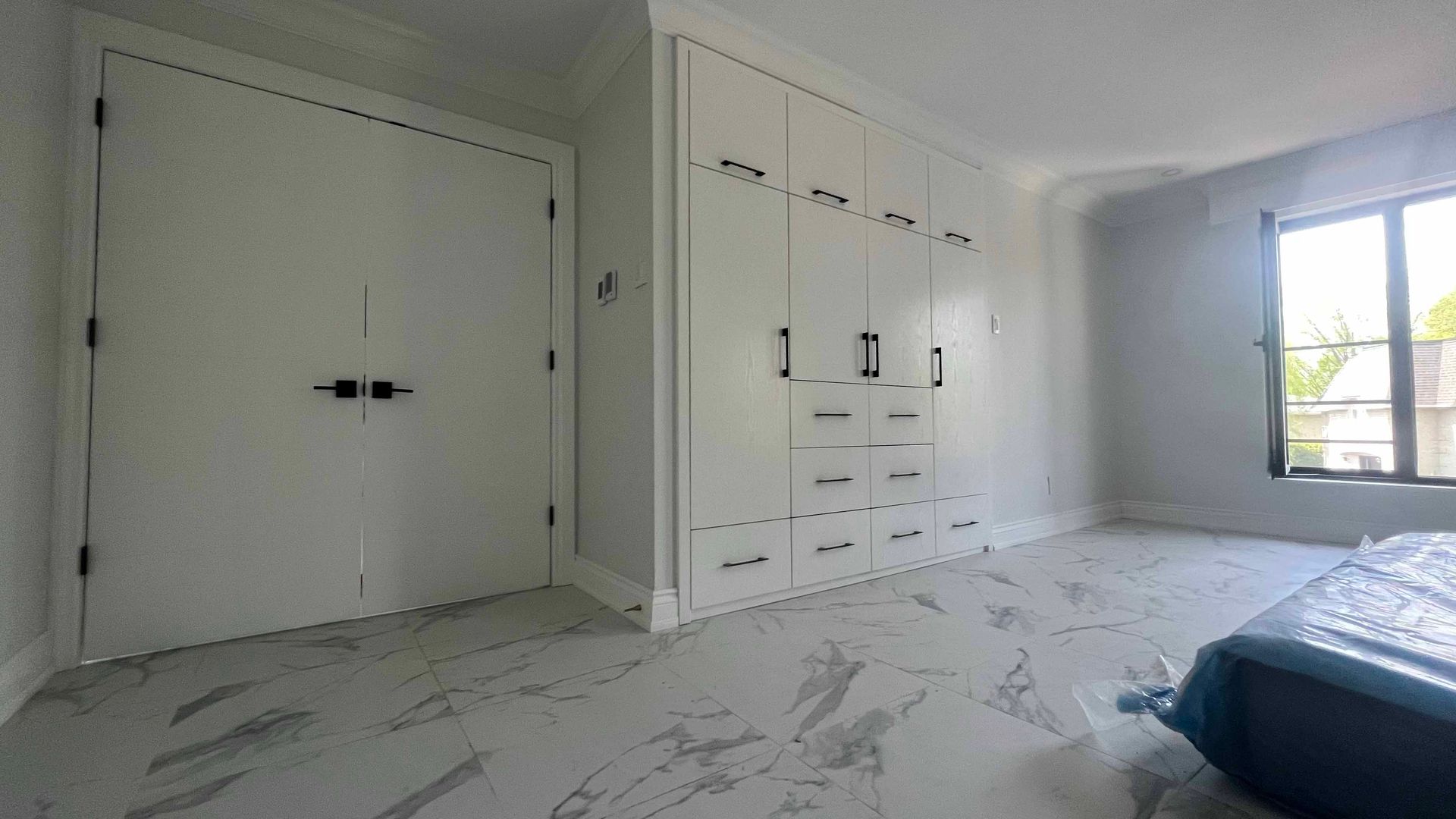 A bedroom with a bed , closets , and a window.