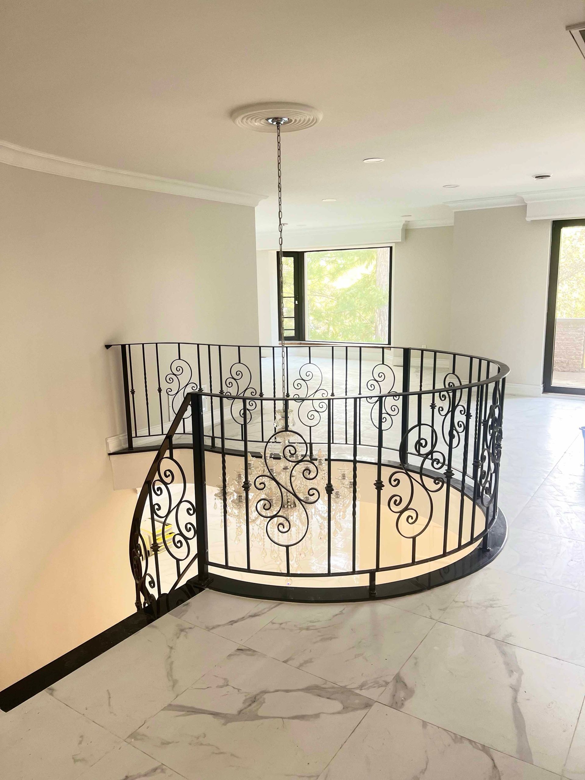 There is a staircase with a wrought iron railing in the middle of the room.