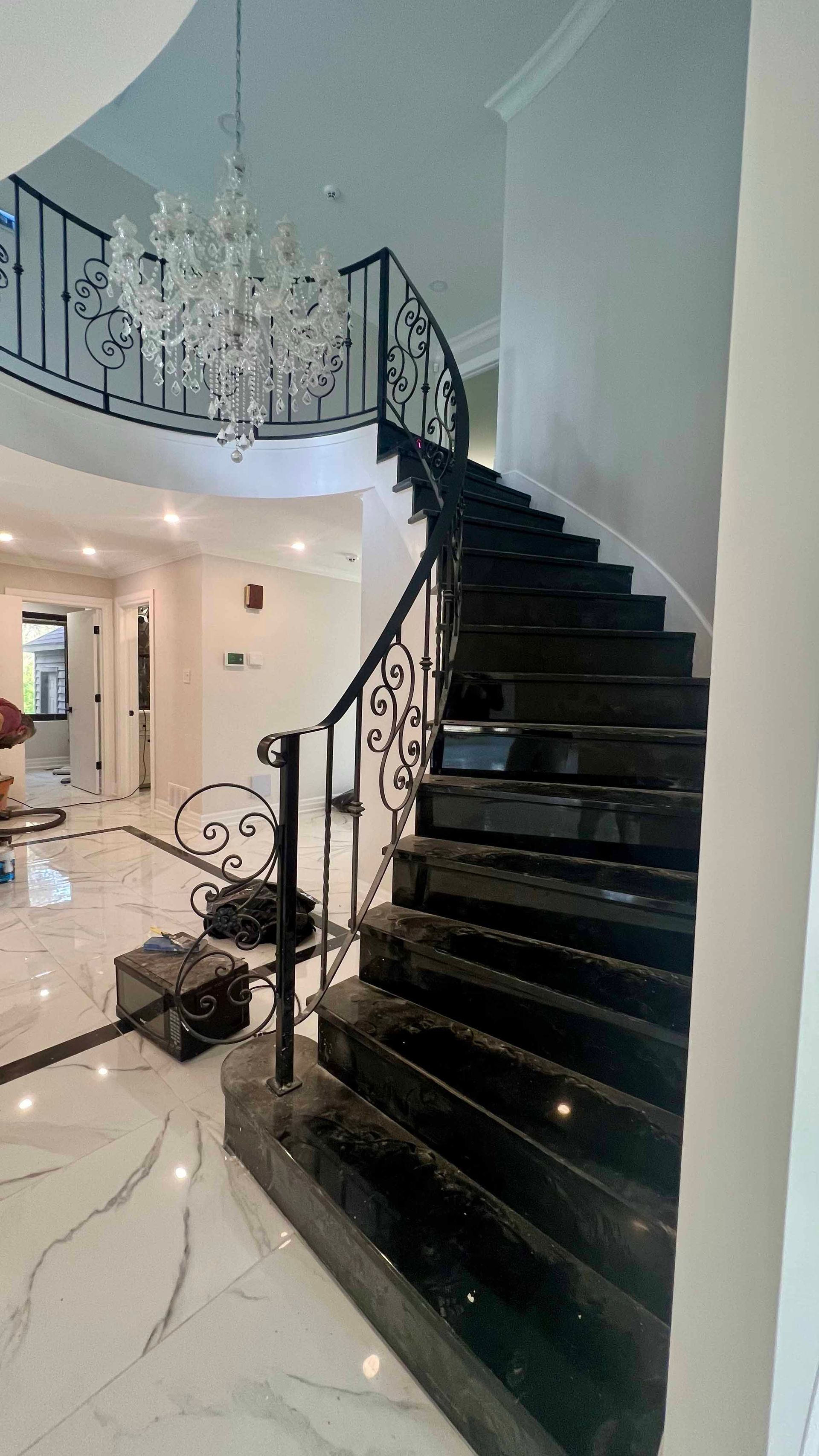 A black spiral staircase with a wrought iron railing in a house.