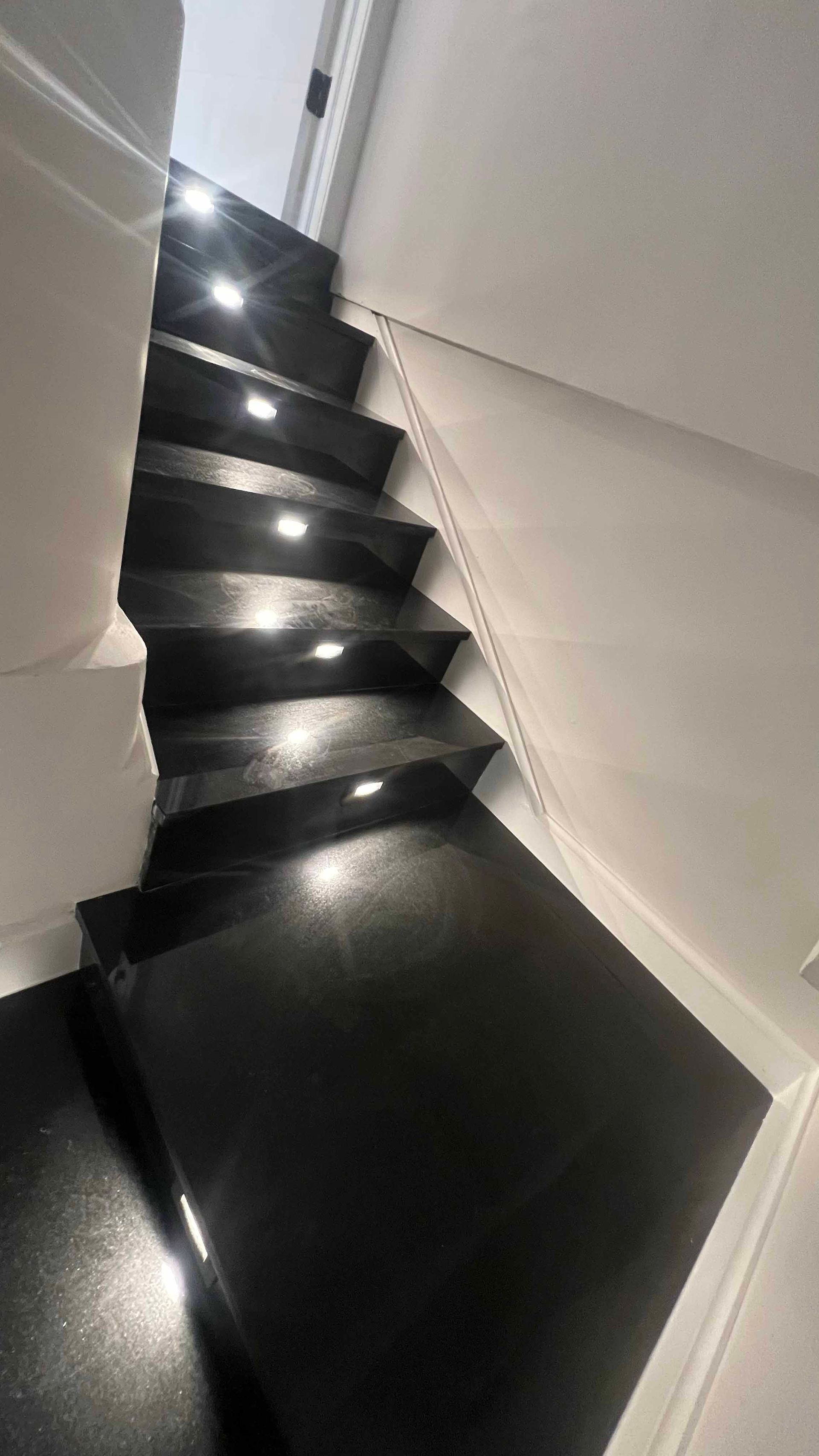A close up of a set of black stairs with lights on them.
