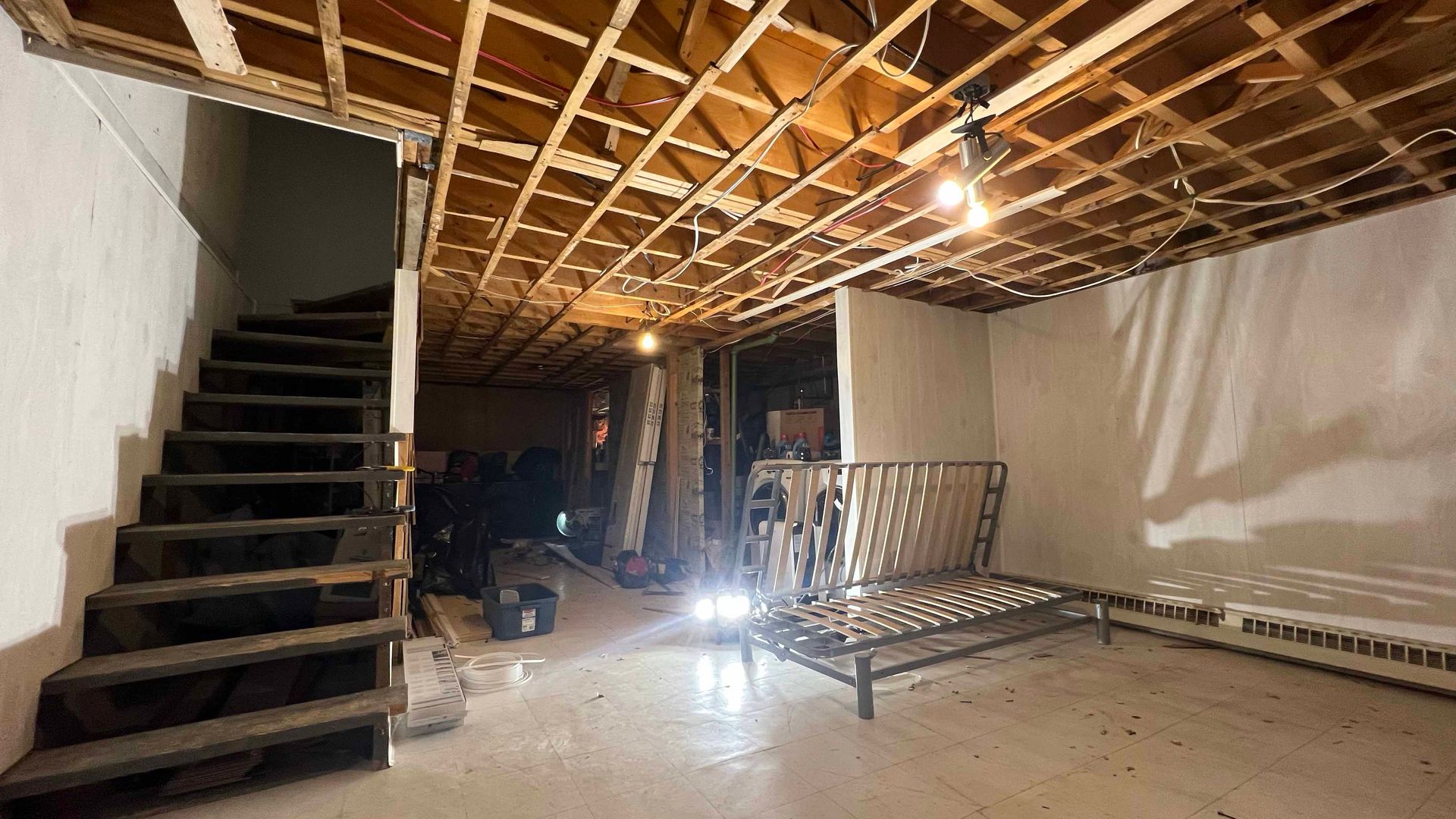 A basement with stairs and a bed in it.