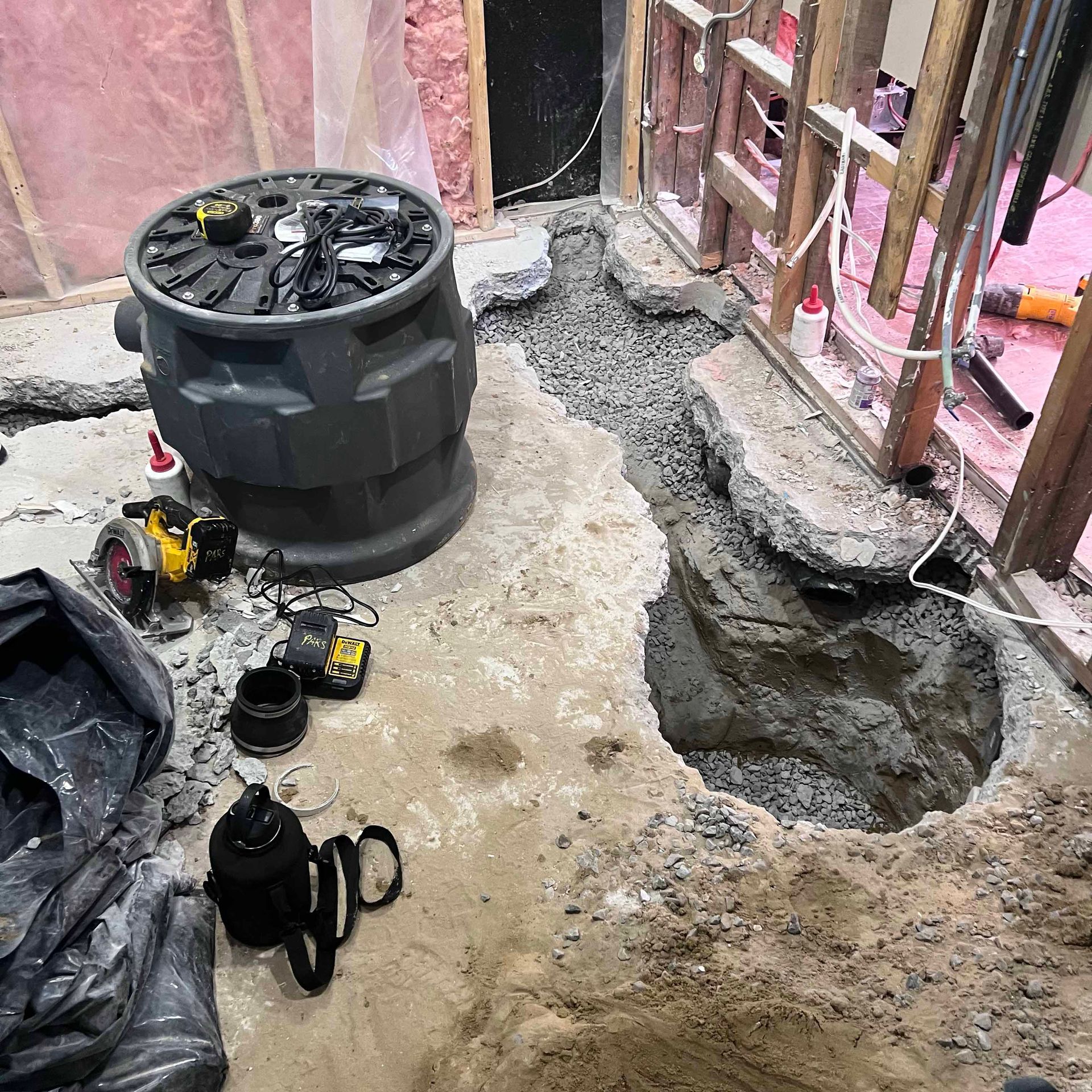 A pump is sitting on top of a pile of dirt next to a hole in the ground.