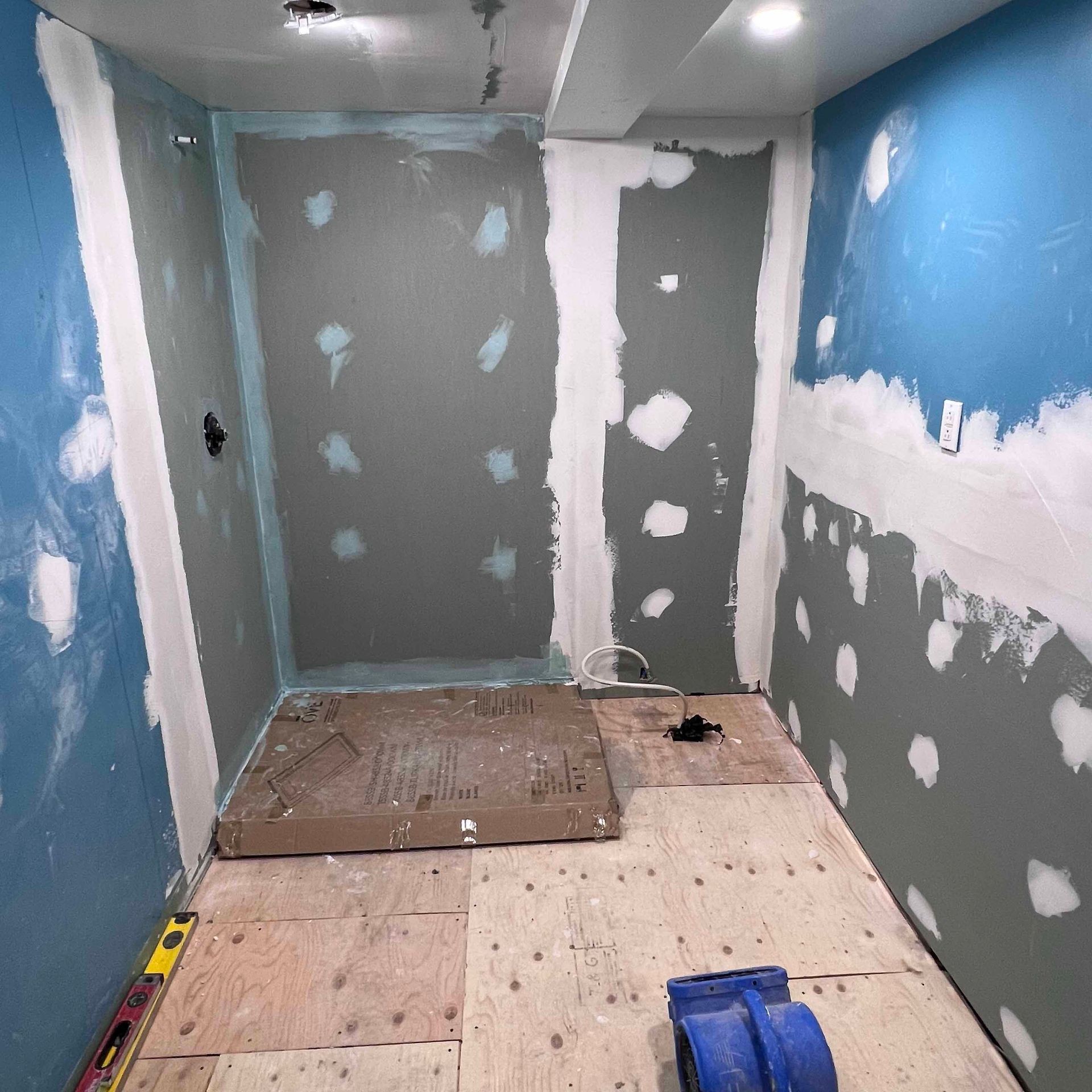 A room with blue walls and a wooden floor is being remodeled.