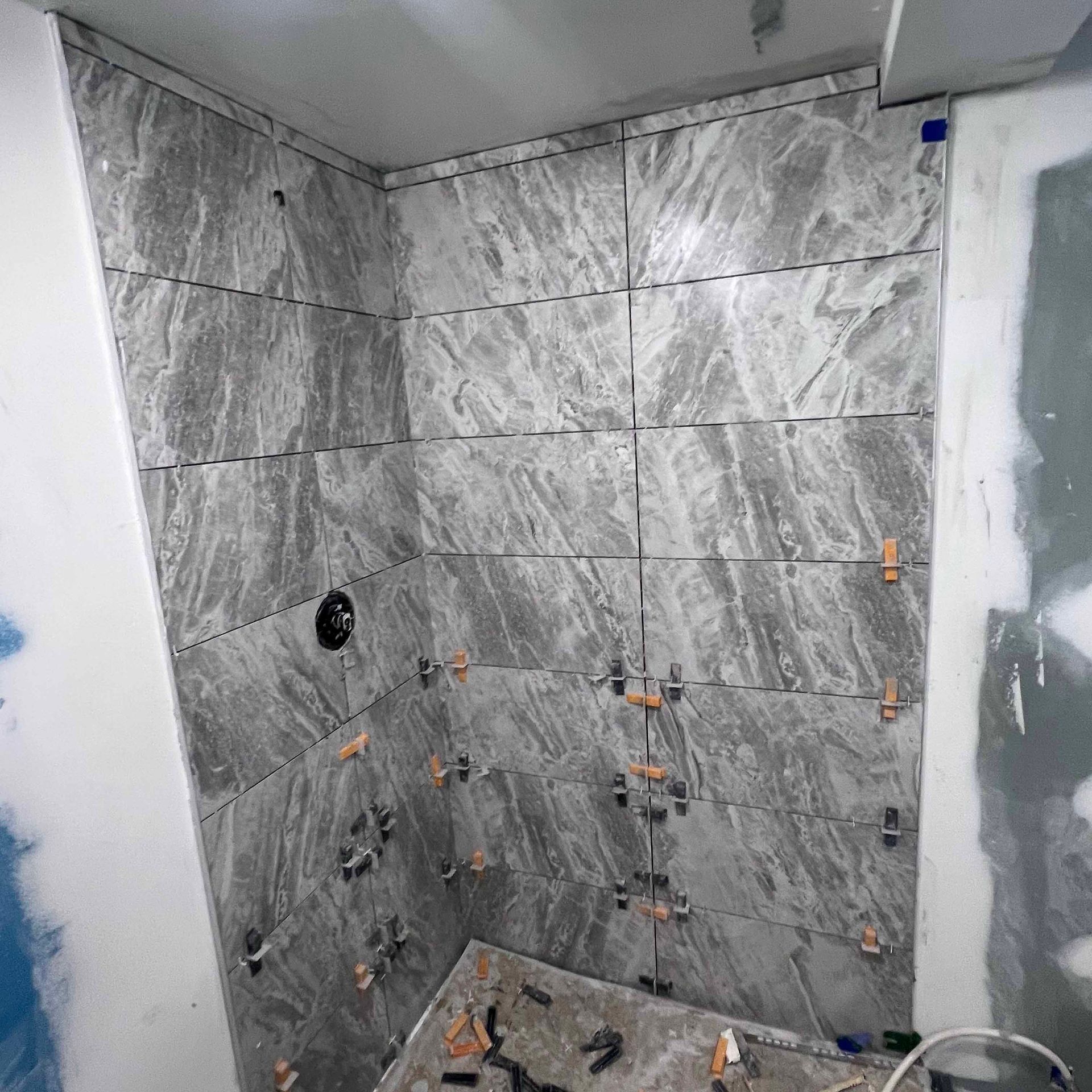 A bathroom under construction with tiles being installed on the wall.