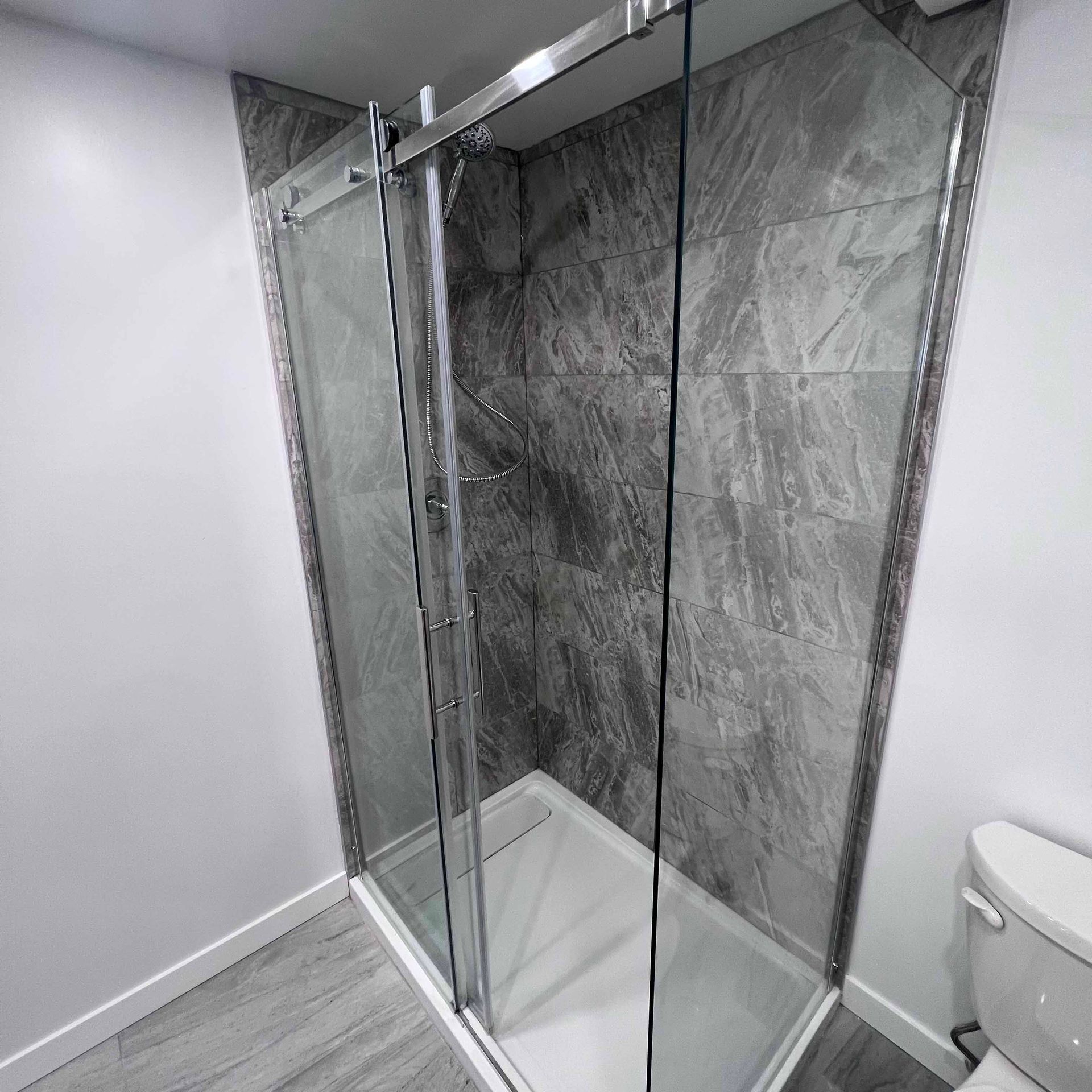 A bathroom with a sliding glass shower door and a toilet.