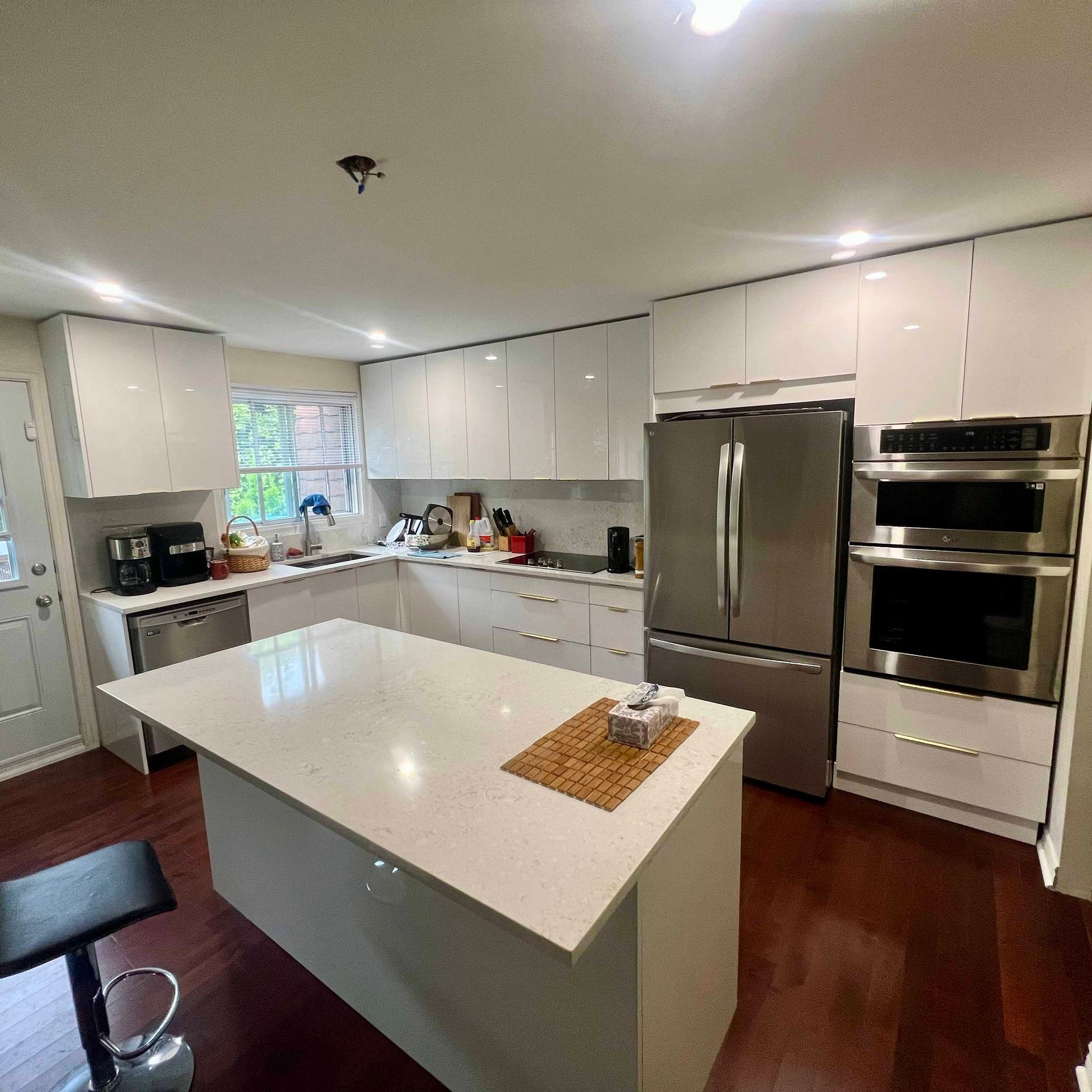 A kitchen with white cabinets , stainless steel appliances , and a large island.