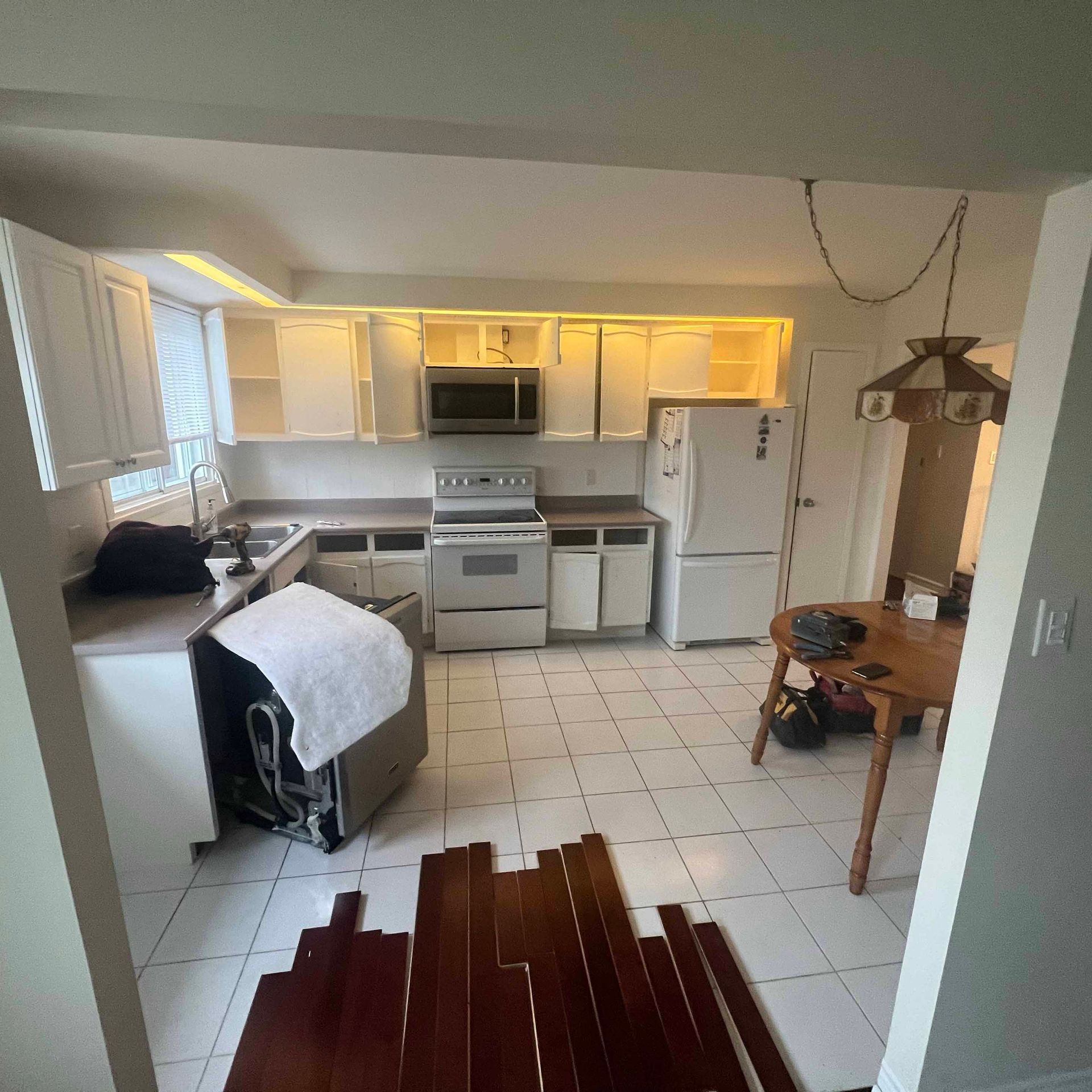 A kitchen with hardwood floors and white cabinets