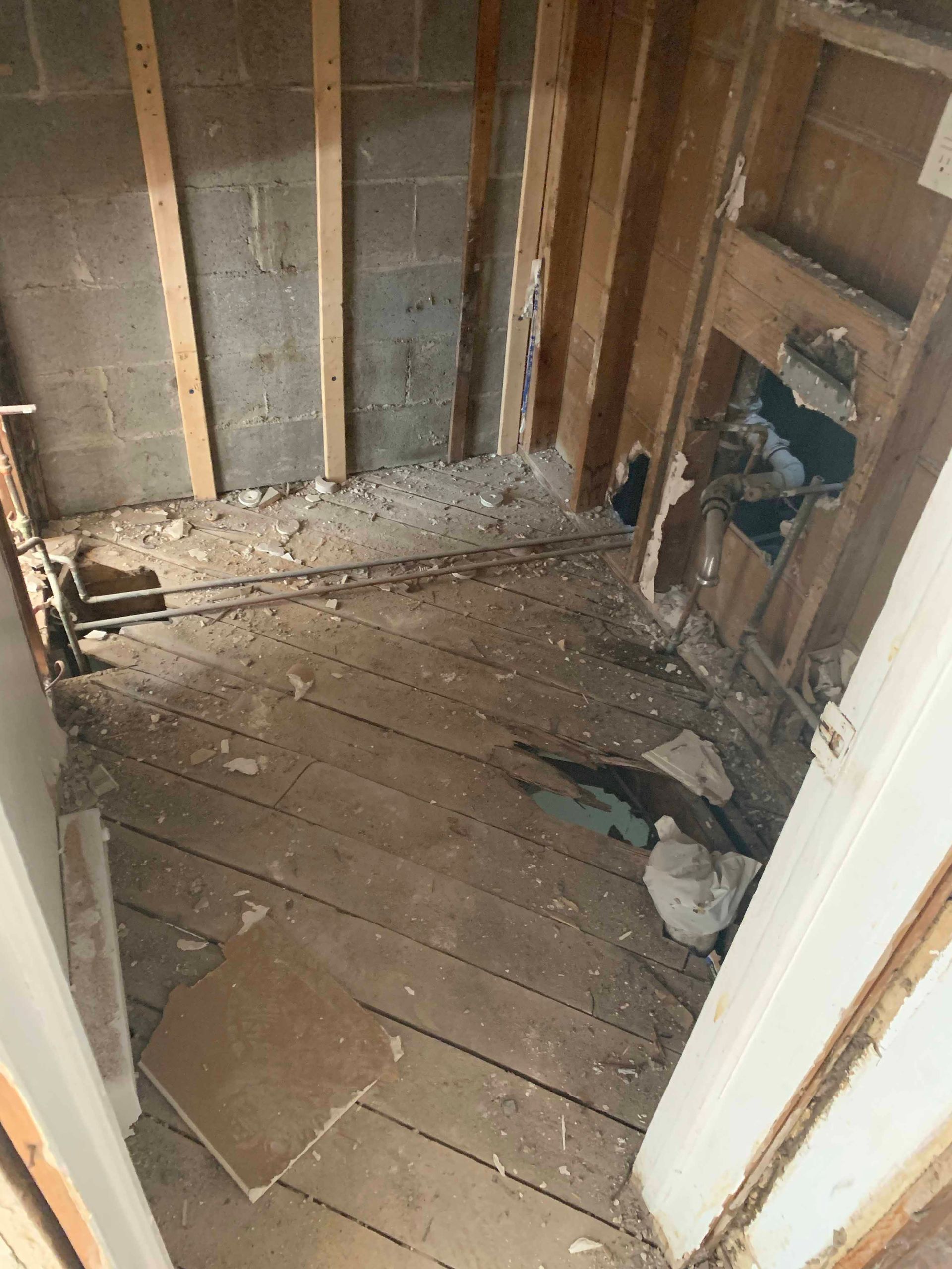 A room with a wooden floor and a hole in the wall.