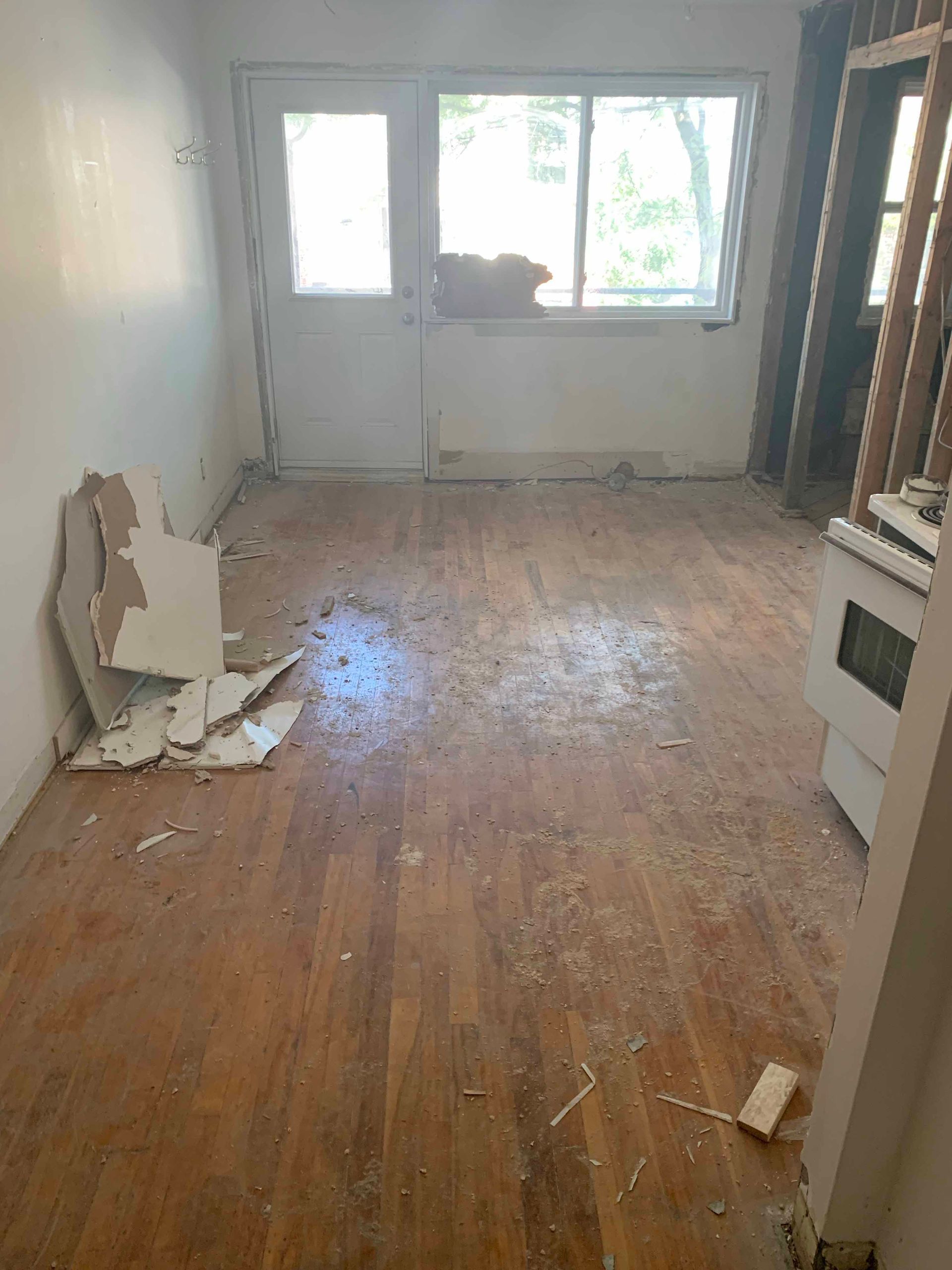 A living room with a wooden floor and a white stove.