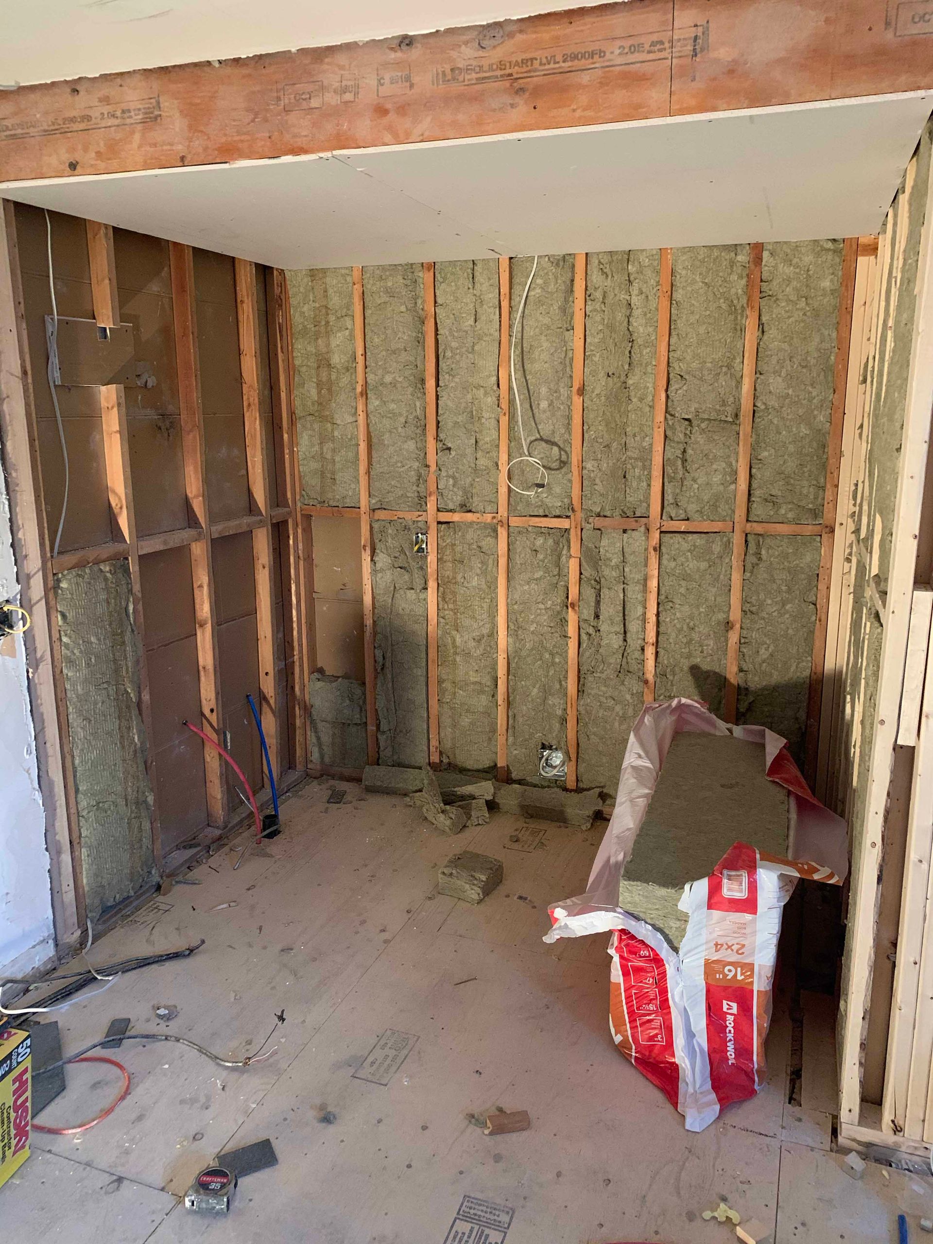 A room with a lot of wooden walls and a bag of insulation on the floor.