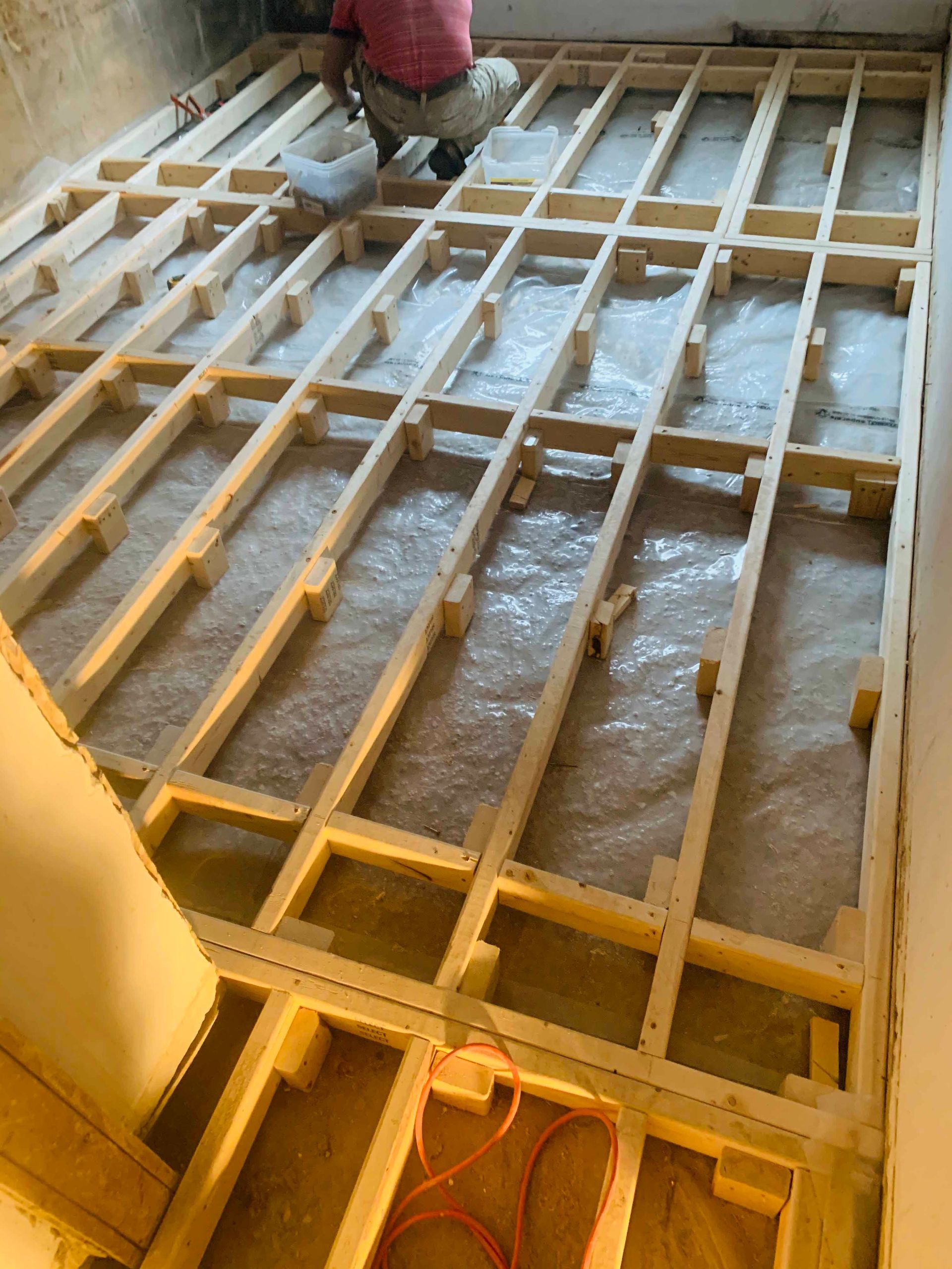 A person is working on a wooden floor in a room.