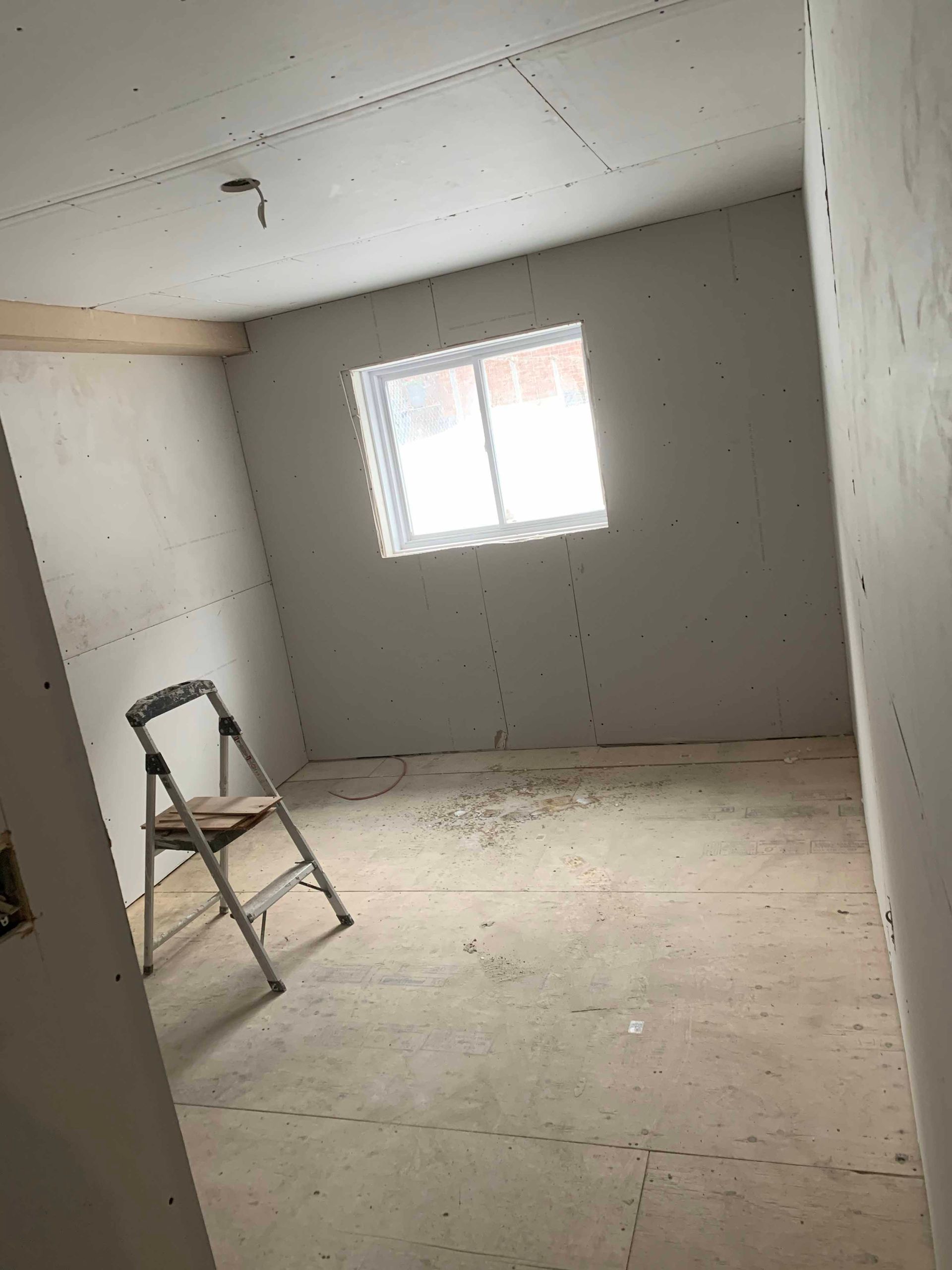 An empty room with a ladder and a window.
