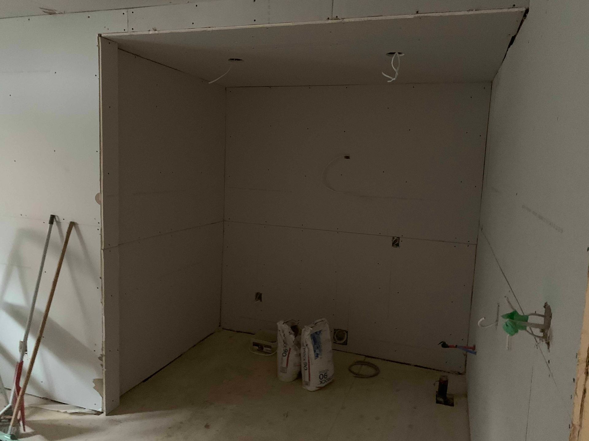 A room with a lot of drywall and a broom in it.