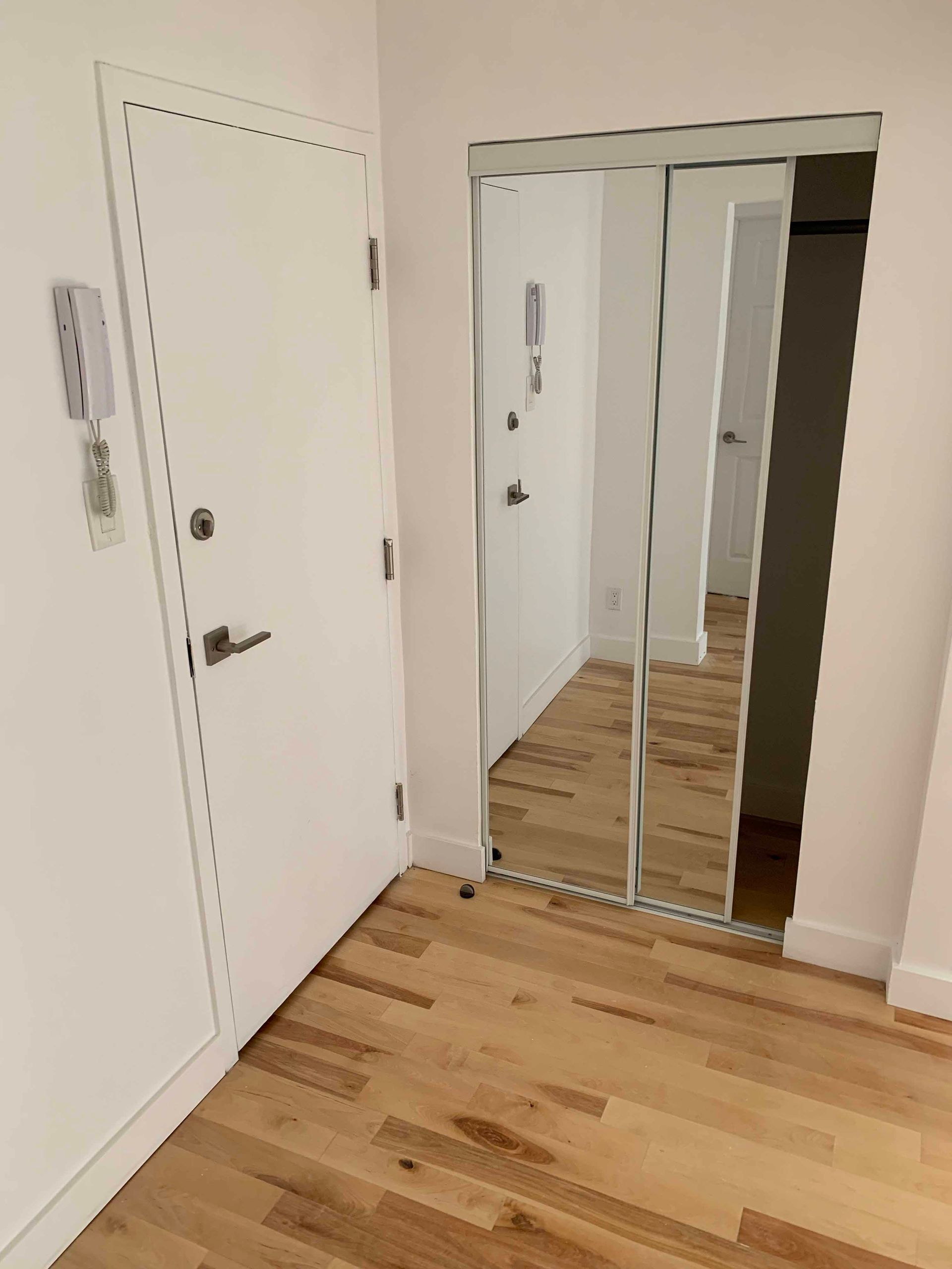 A hallway with a door and a mirror on the wall