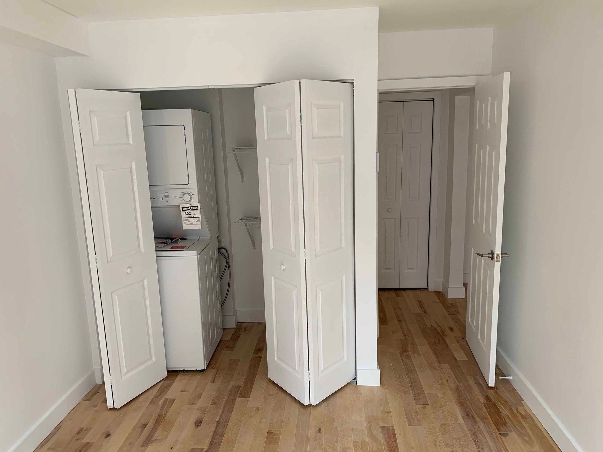 Small room with washer/dryer behind folding doors. Open door leads to another room.