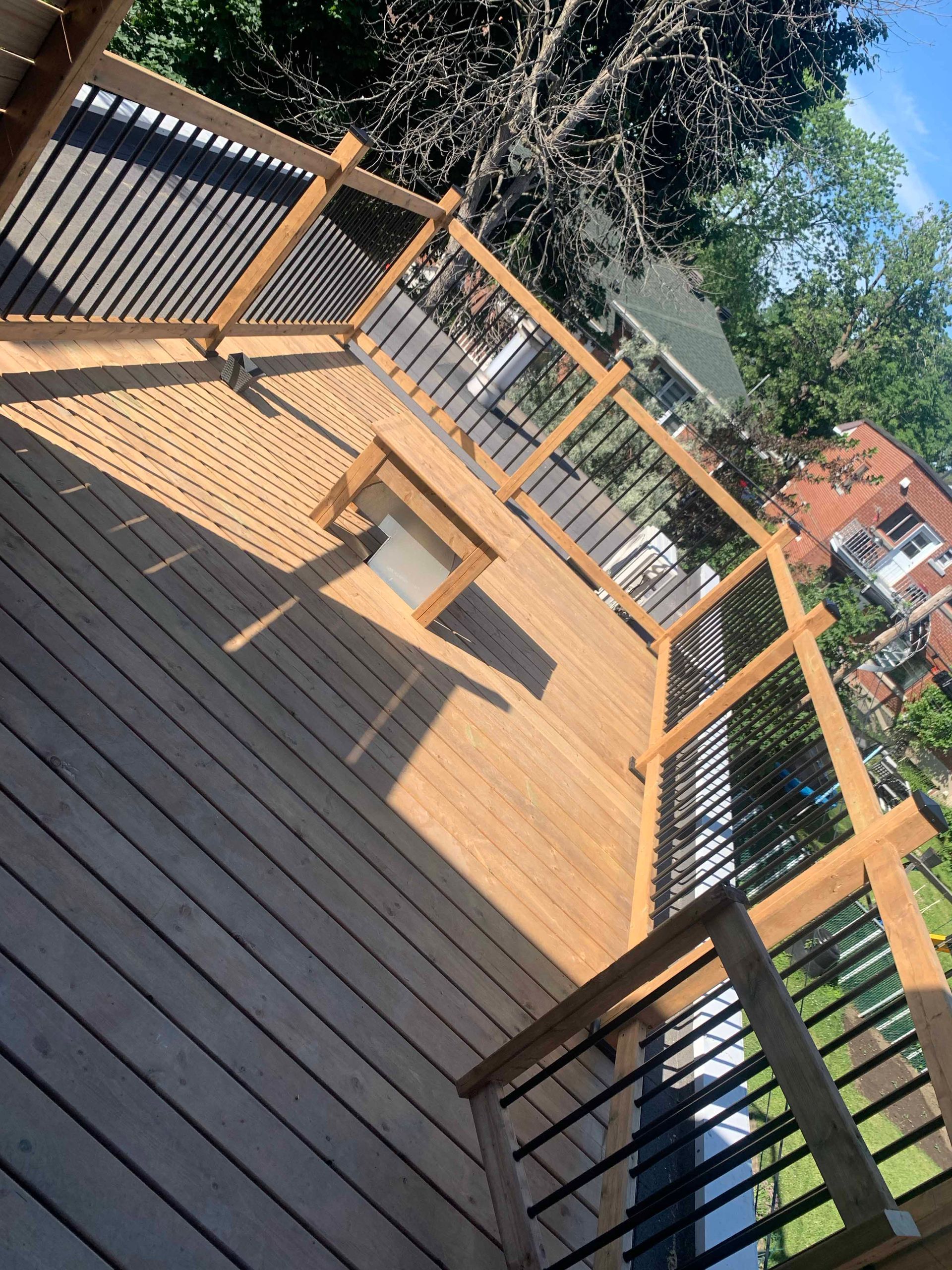 A wooden deck with a metal railing and a bench