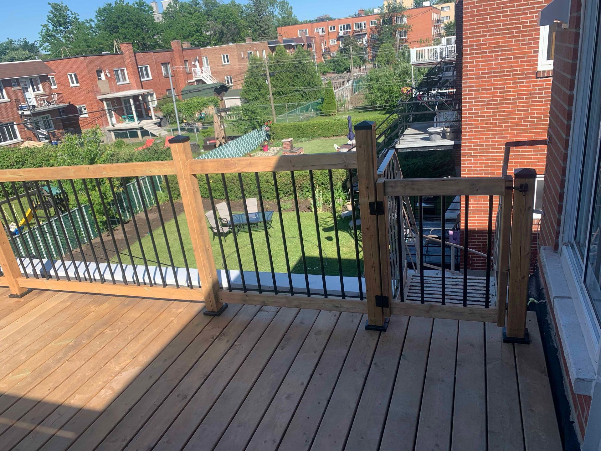 A wooden deck with a metal railing and a view of a city.