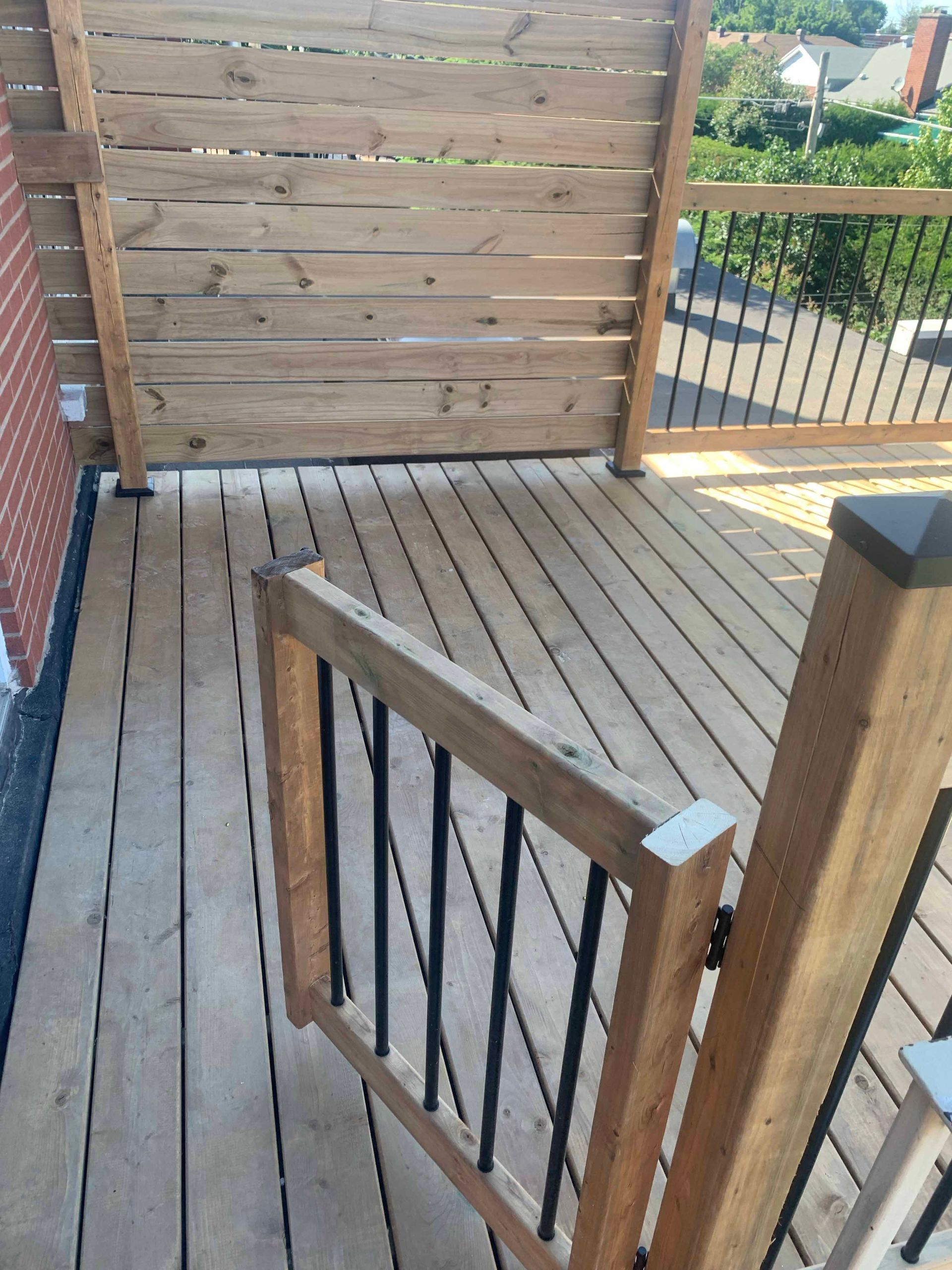 A wooden deck with a metal railing and a wooden fence.