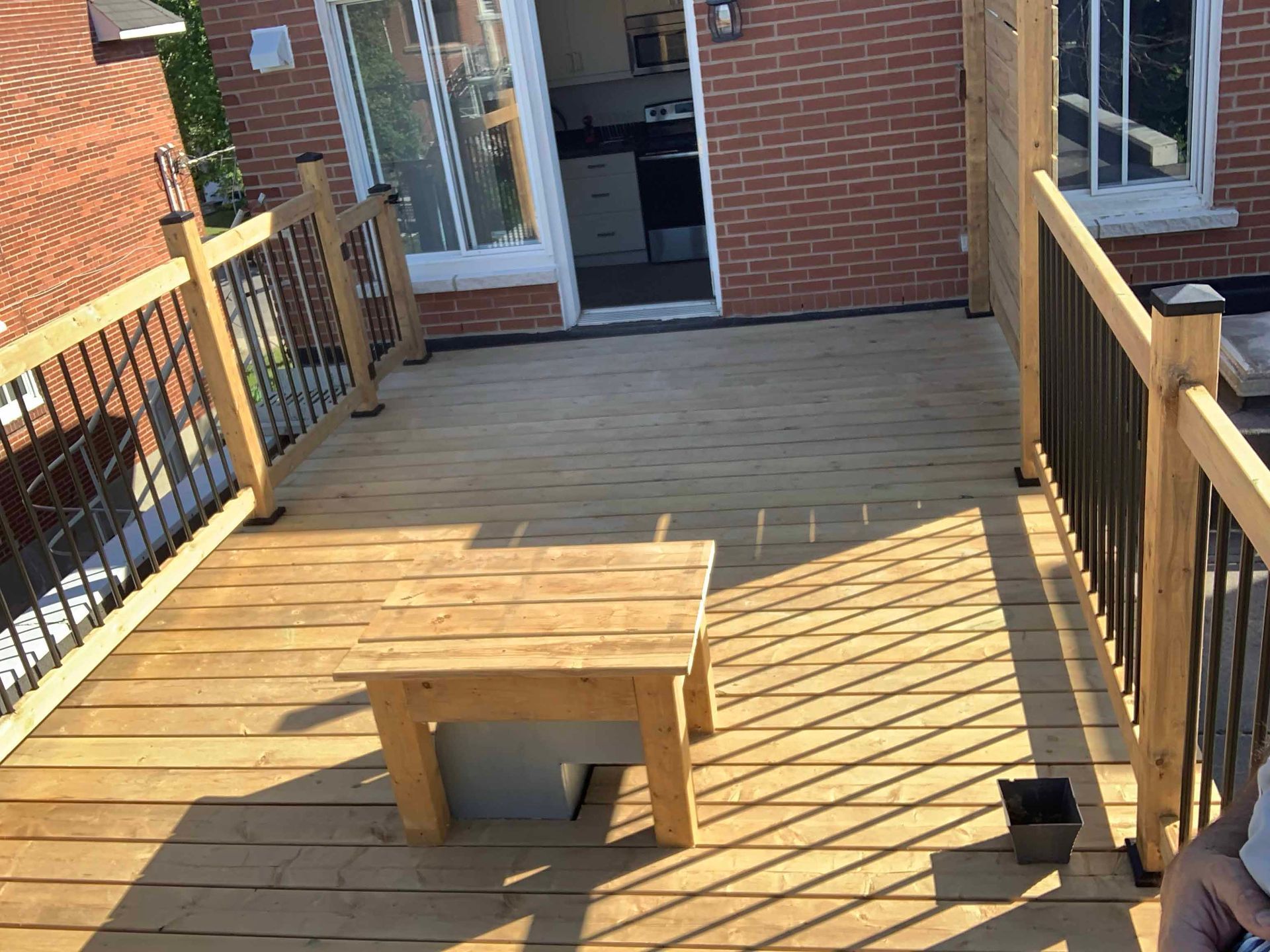 A person is sitting on a wooden deck next to a brick building.