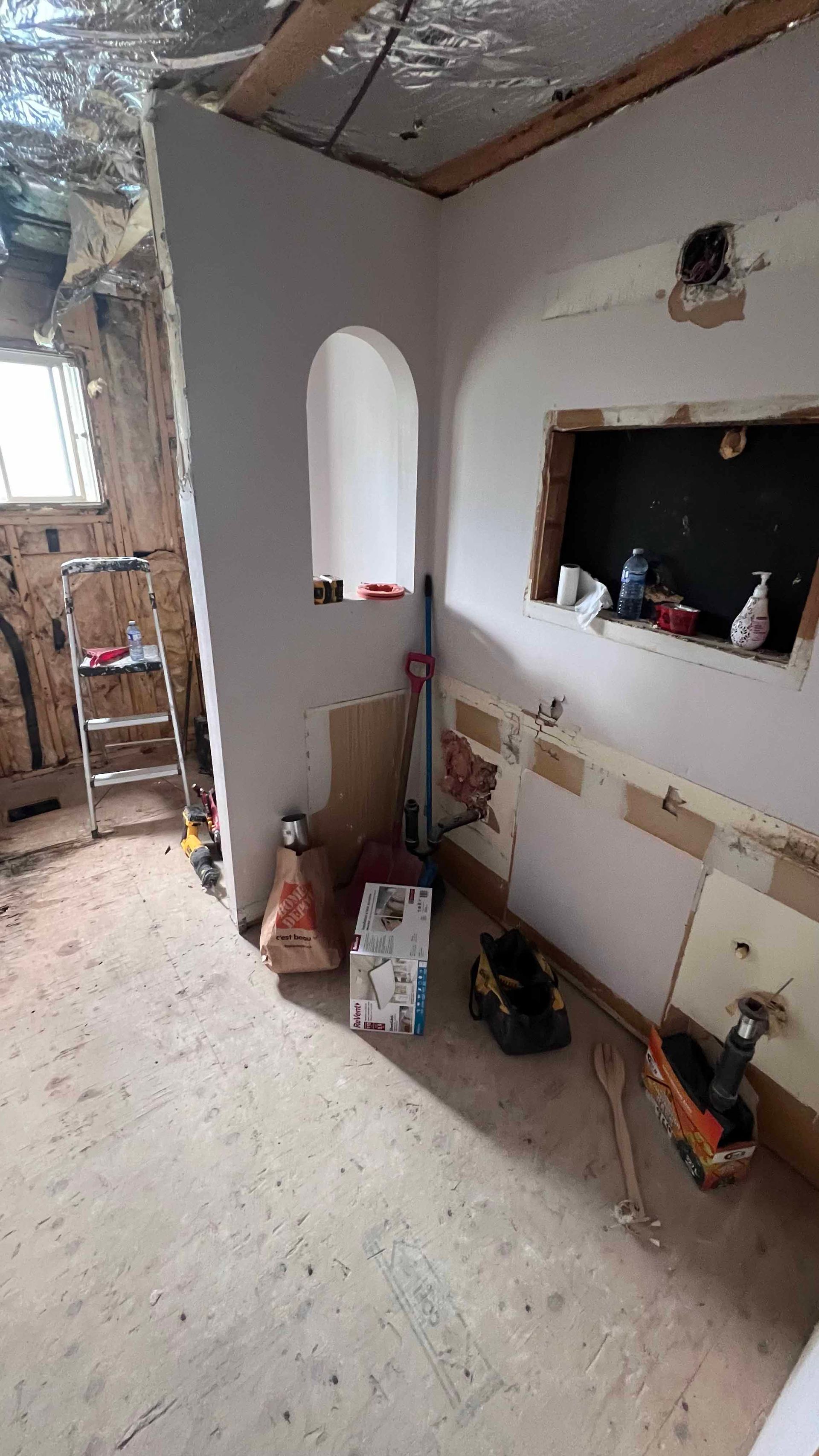 A room with a window and a ladder in it is being remodeled.