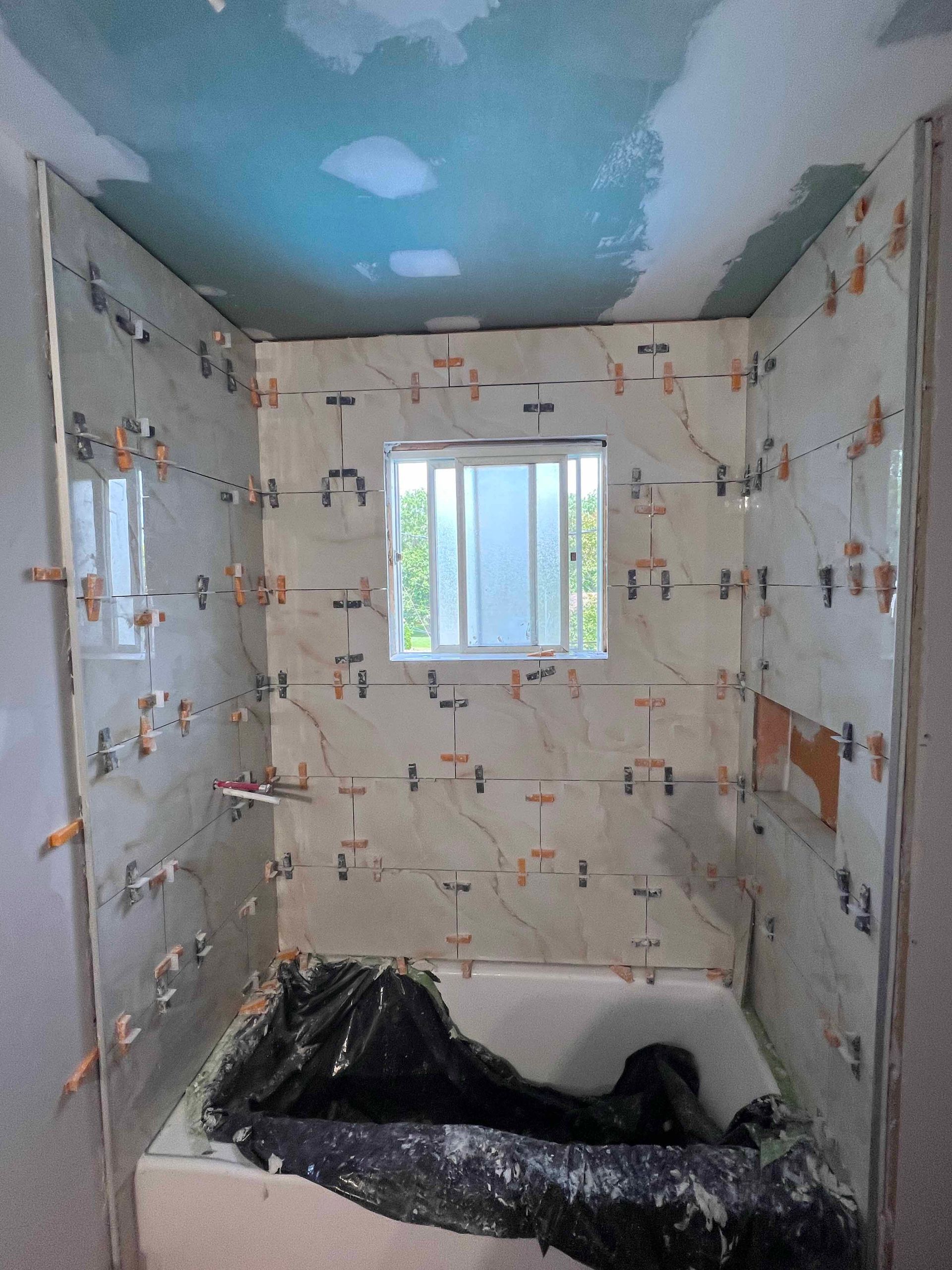 A bathroom under construction with a bathtub and a window.
