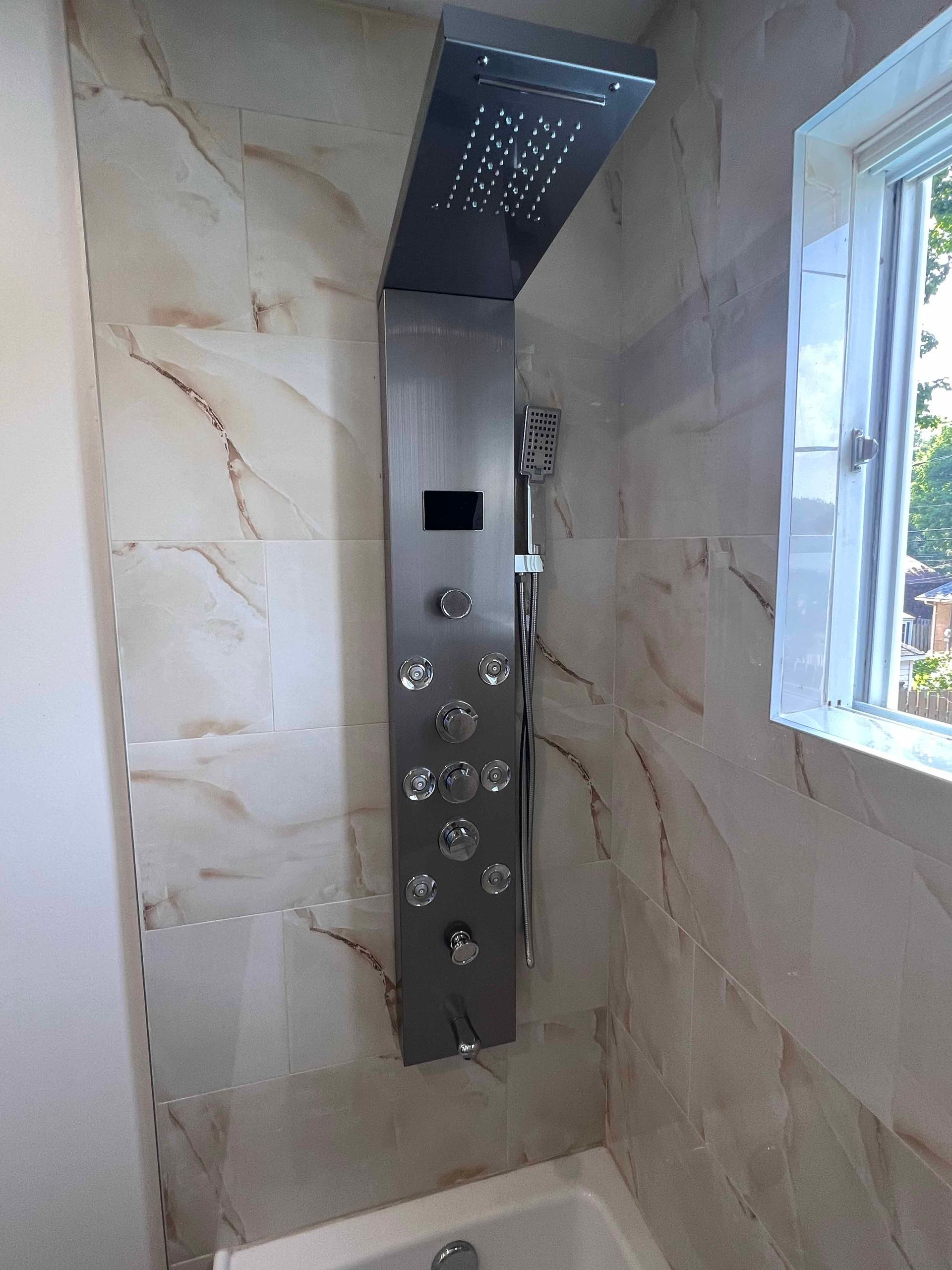 A bathroom with a shower head and a window