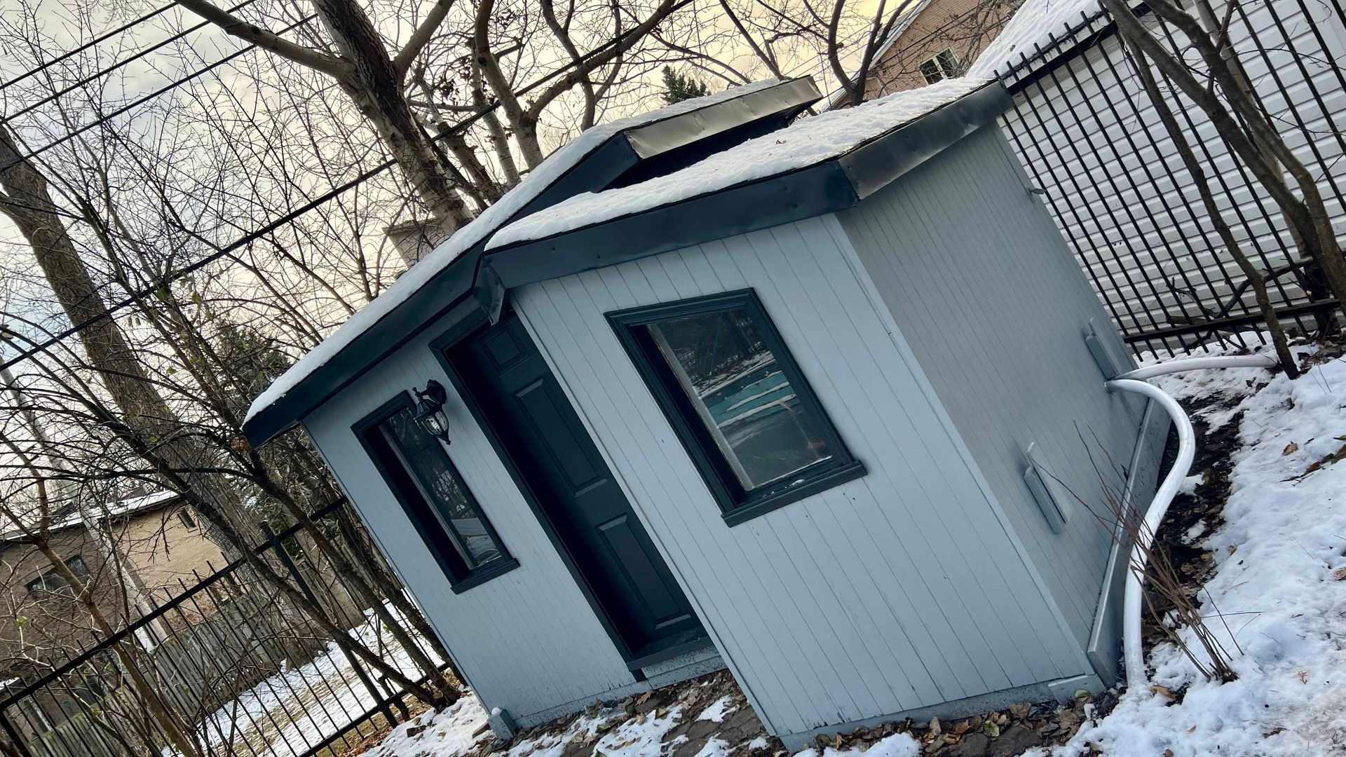 A small house is sitting on the ground in the snow.