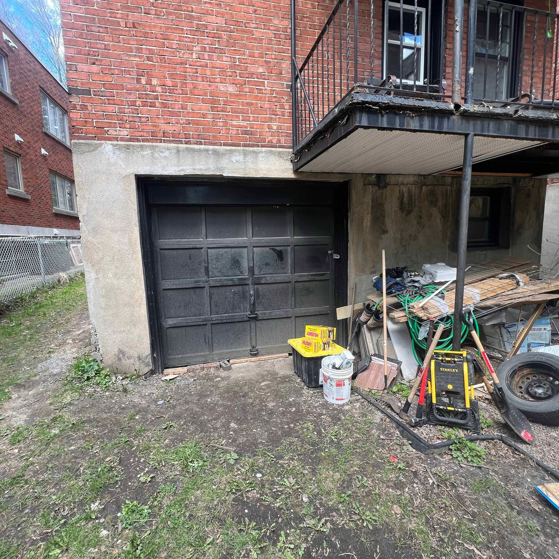 A garage door is sitting in front of a brick building.