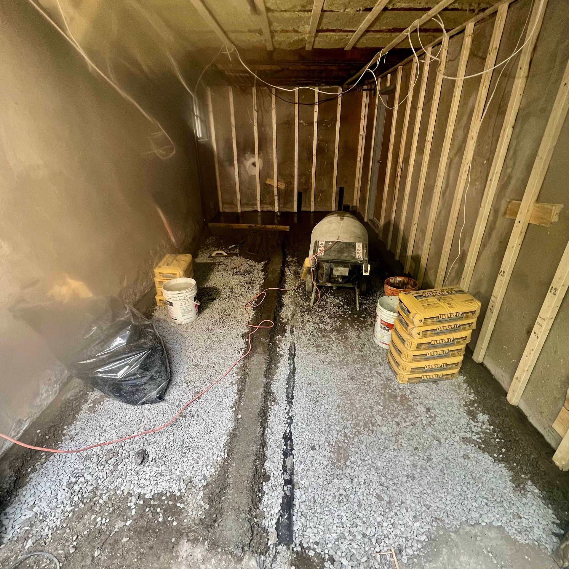 A room with a lot of gravel on the floor and a wheelbarrow in it.