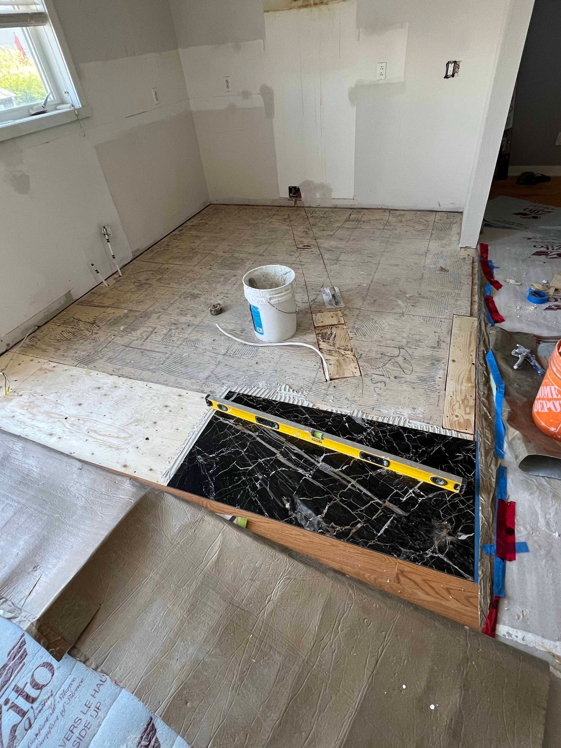 A bathroom under construction with a bucket of paint and a level on the floor.