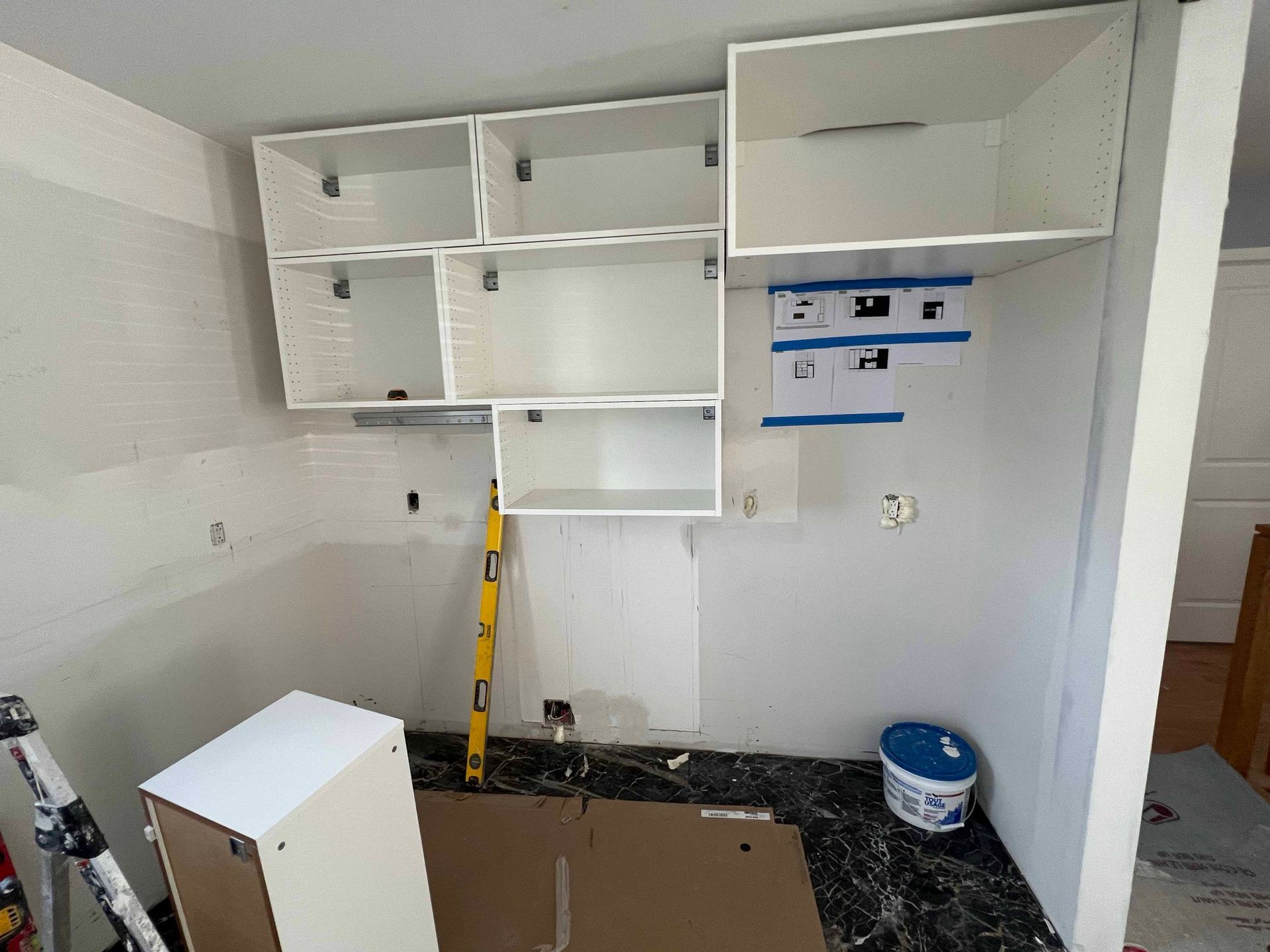 A room with a lot of shelves and a yellow level on the floor.