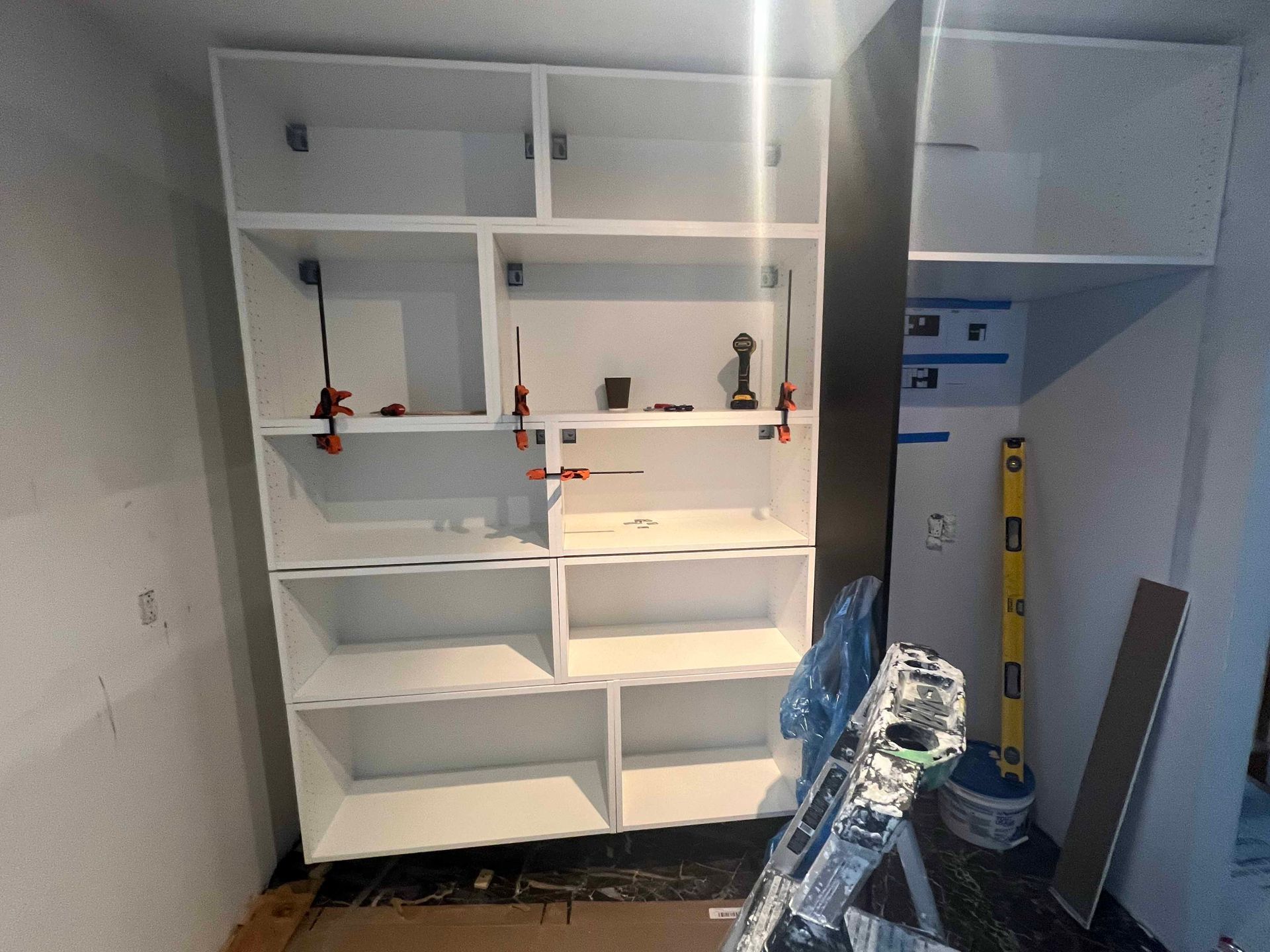 A ladder is sitting next to a shelf in a room.