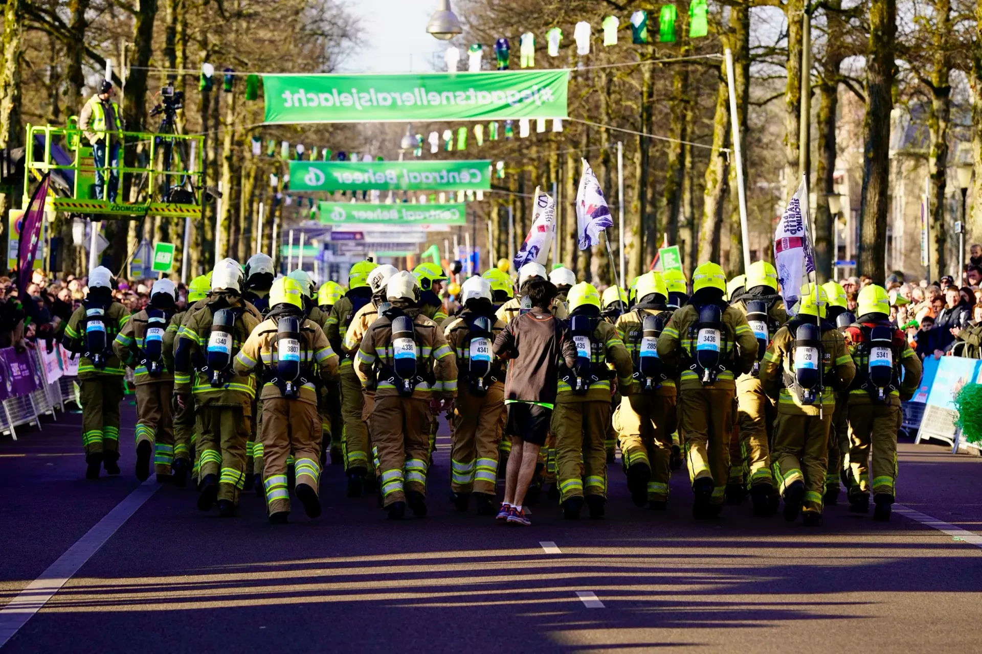 Brandweerteam rent onder de groene spandoeken van Centraal Beheer bij de Midwinter Marathon.
