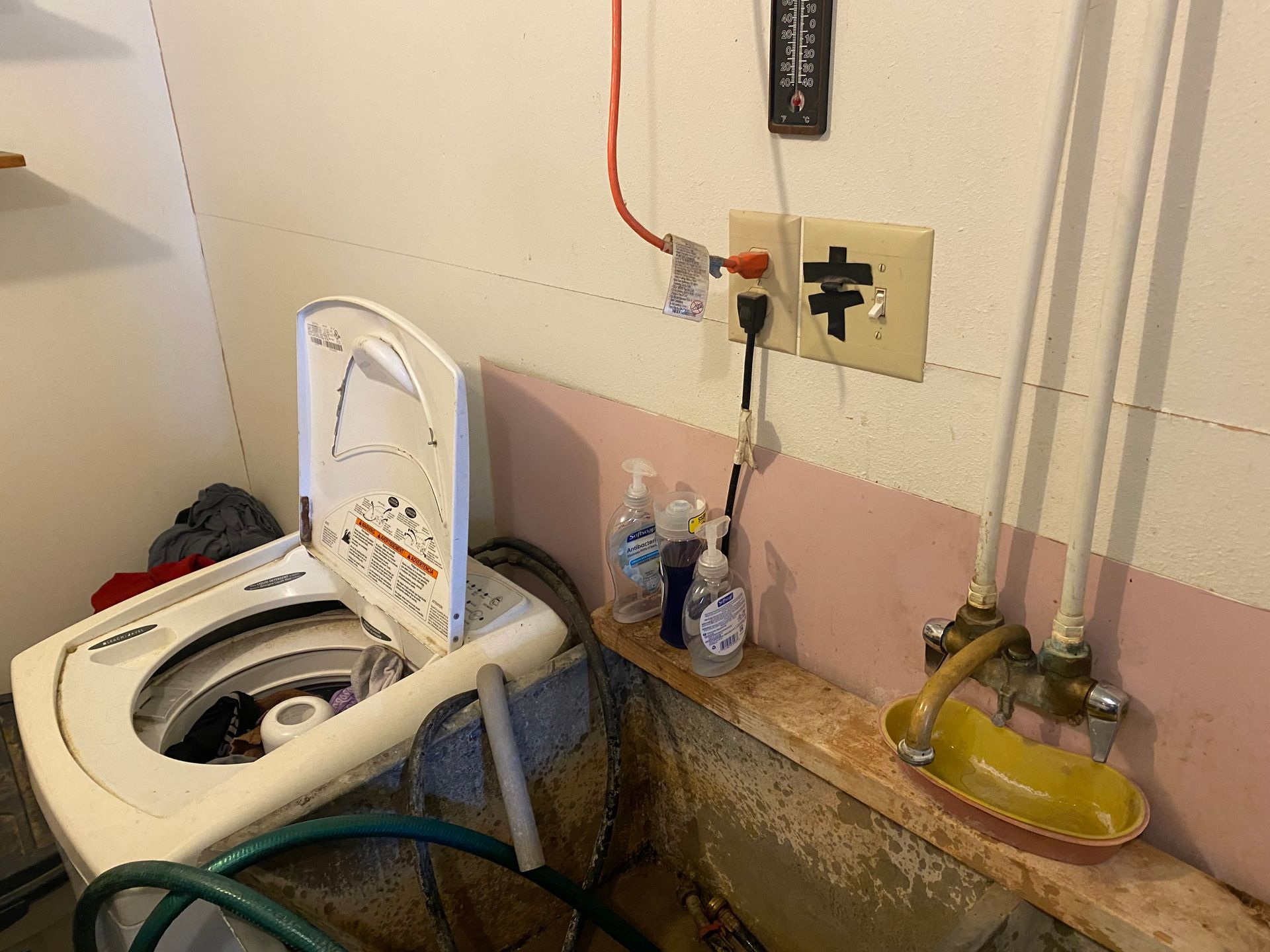 A washing machine is sitting in a bathroom next to a sink.