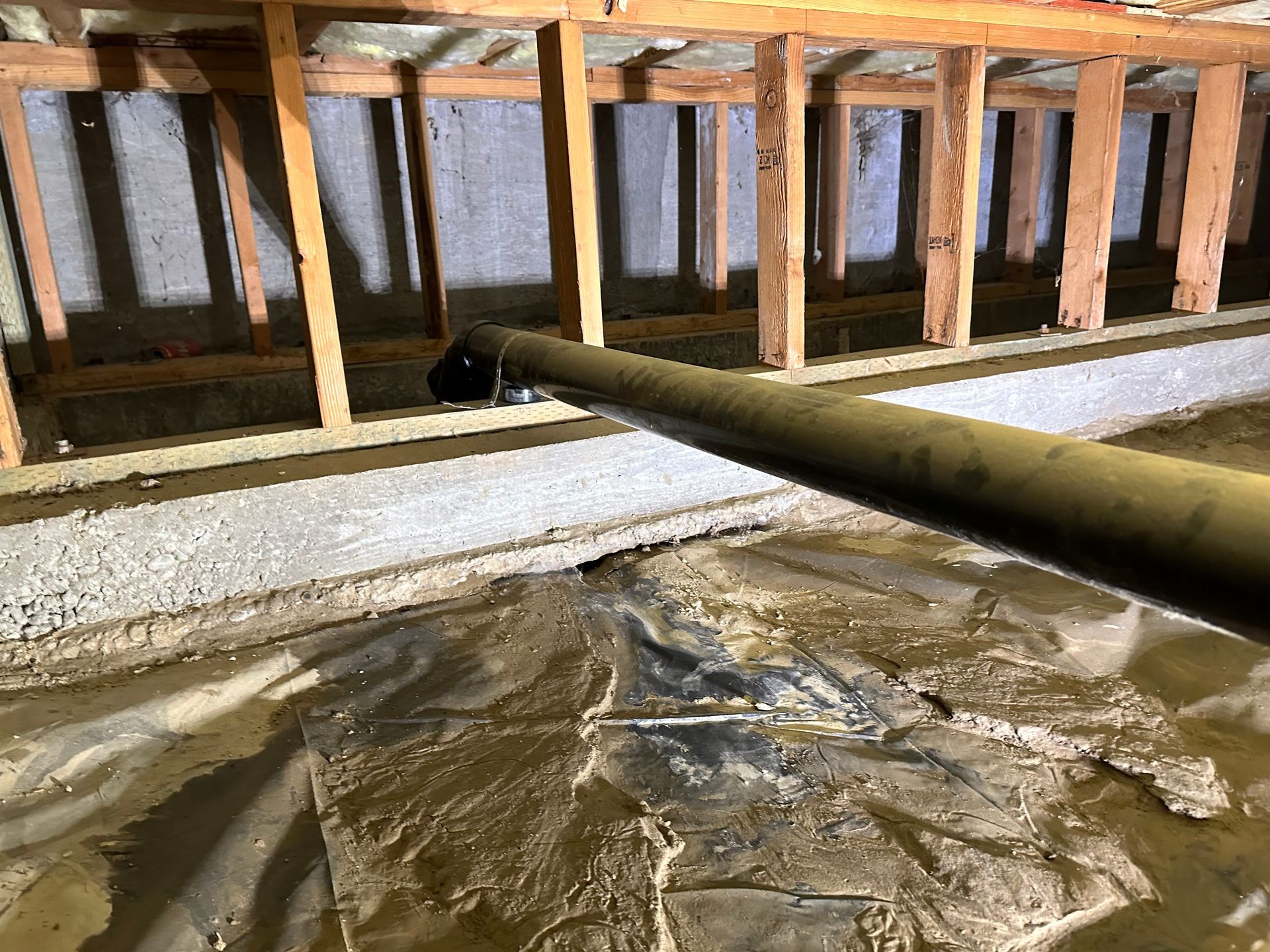 A pipe is hanging from the ceiling of a basement.