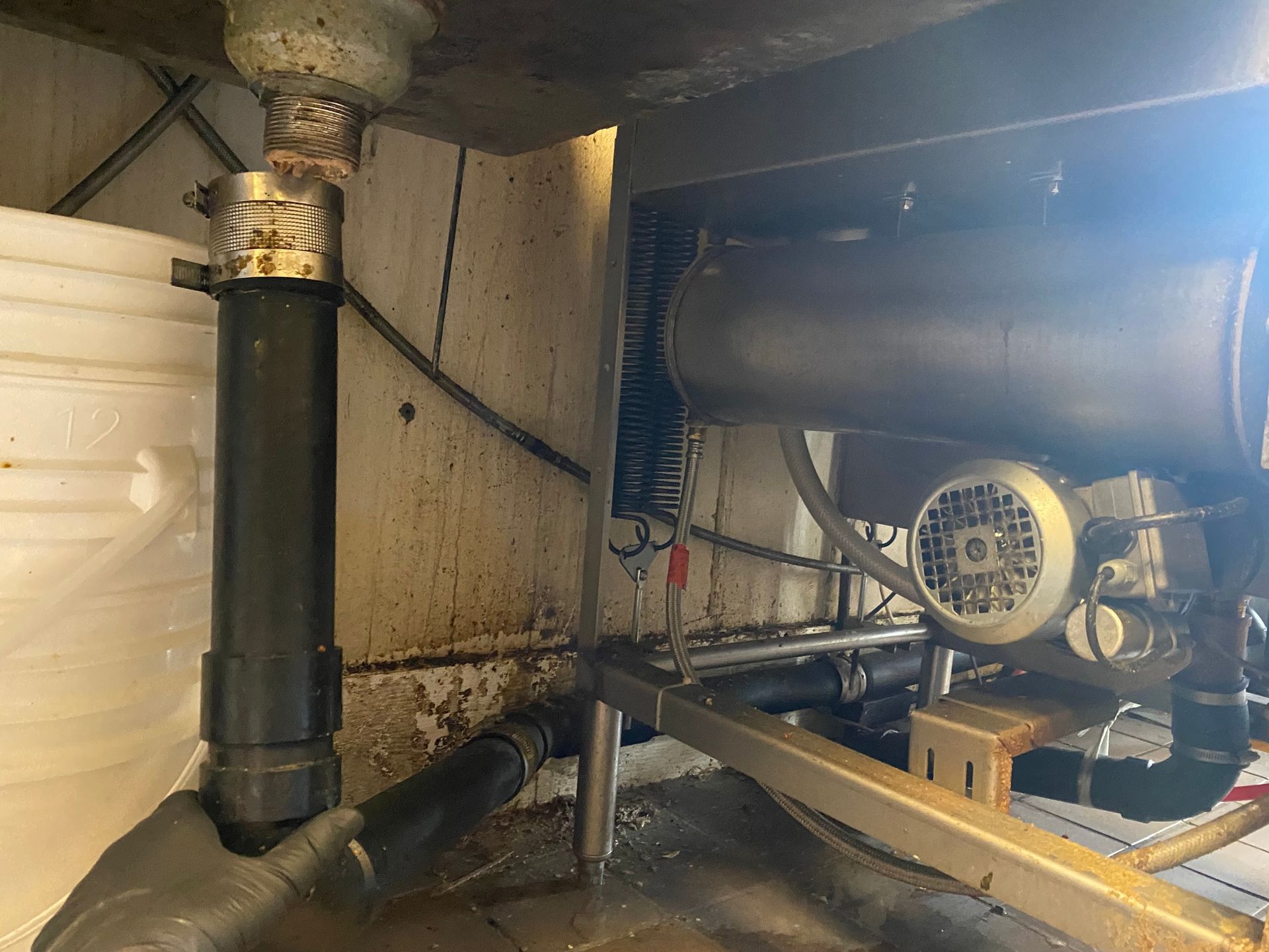 A machine is sitting under a sink in a kitchen.