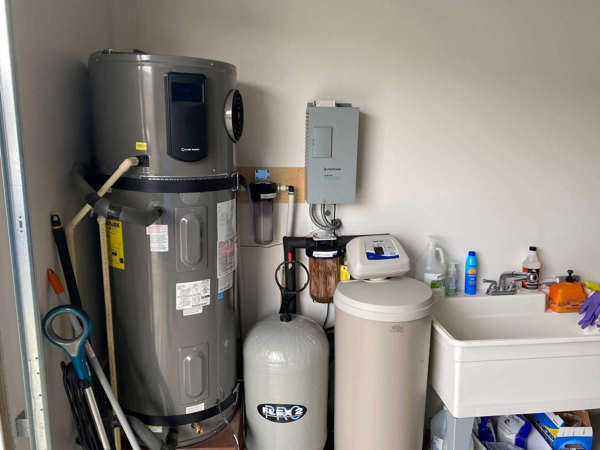 A laundry room with a water heater and a sink.