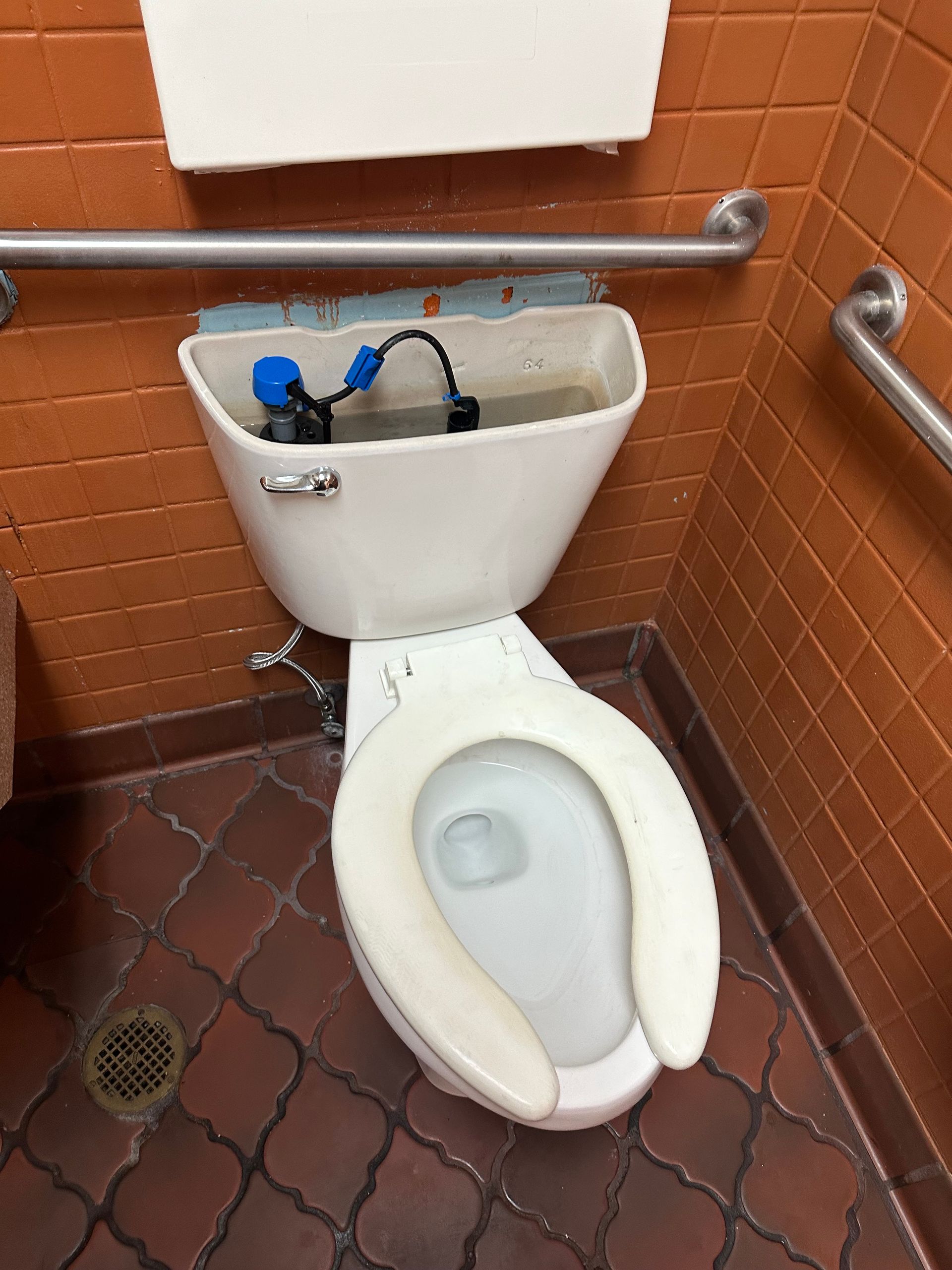 A toilet with a blue hose attached to it in a bathroom.