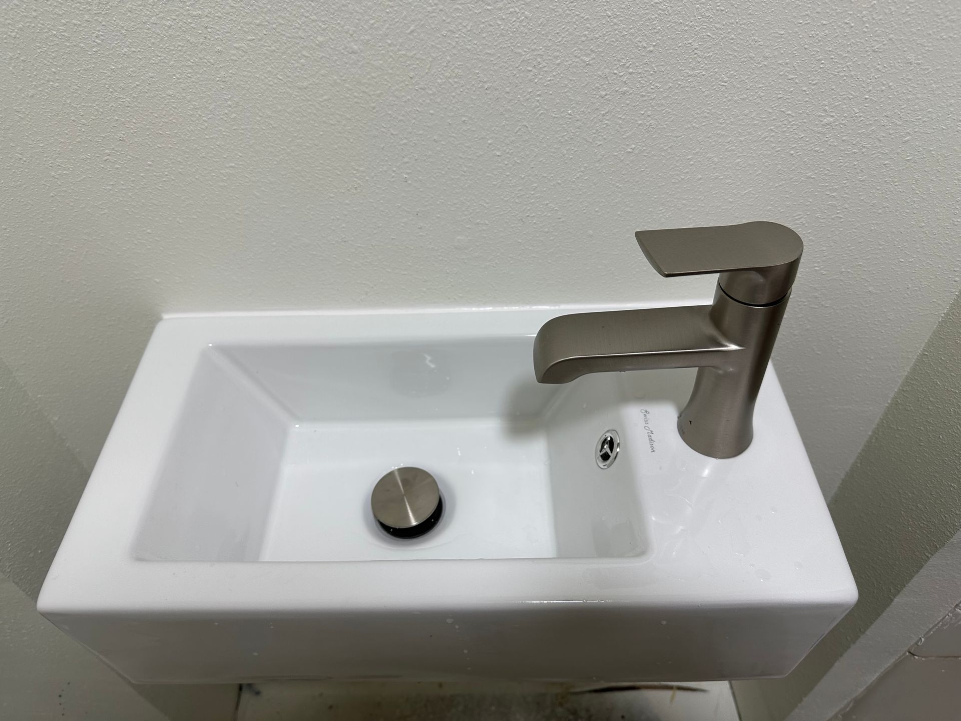 A small white sink with a faucet on it in a bathroom.