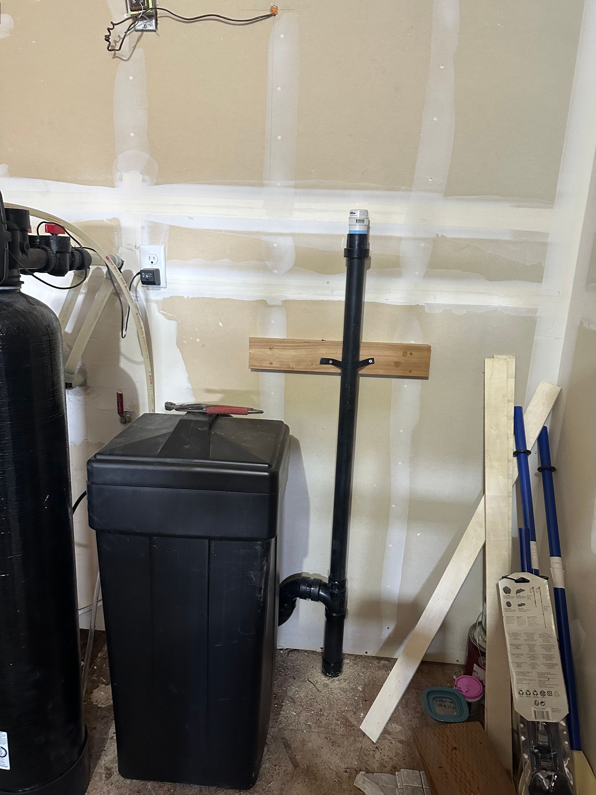 A water softener is sitting in a room next to a wall.