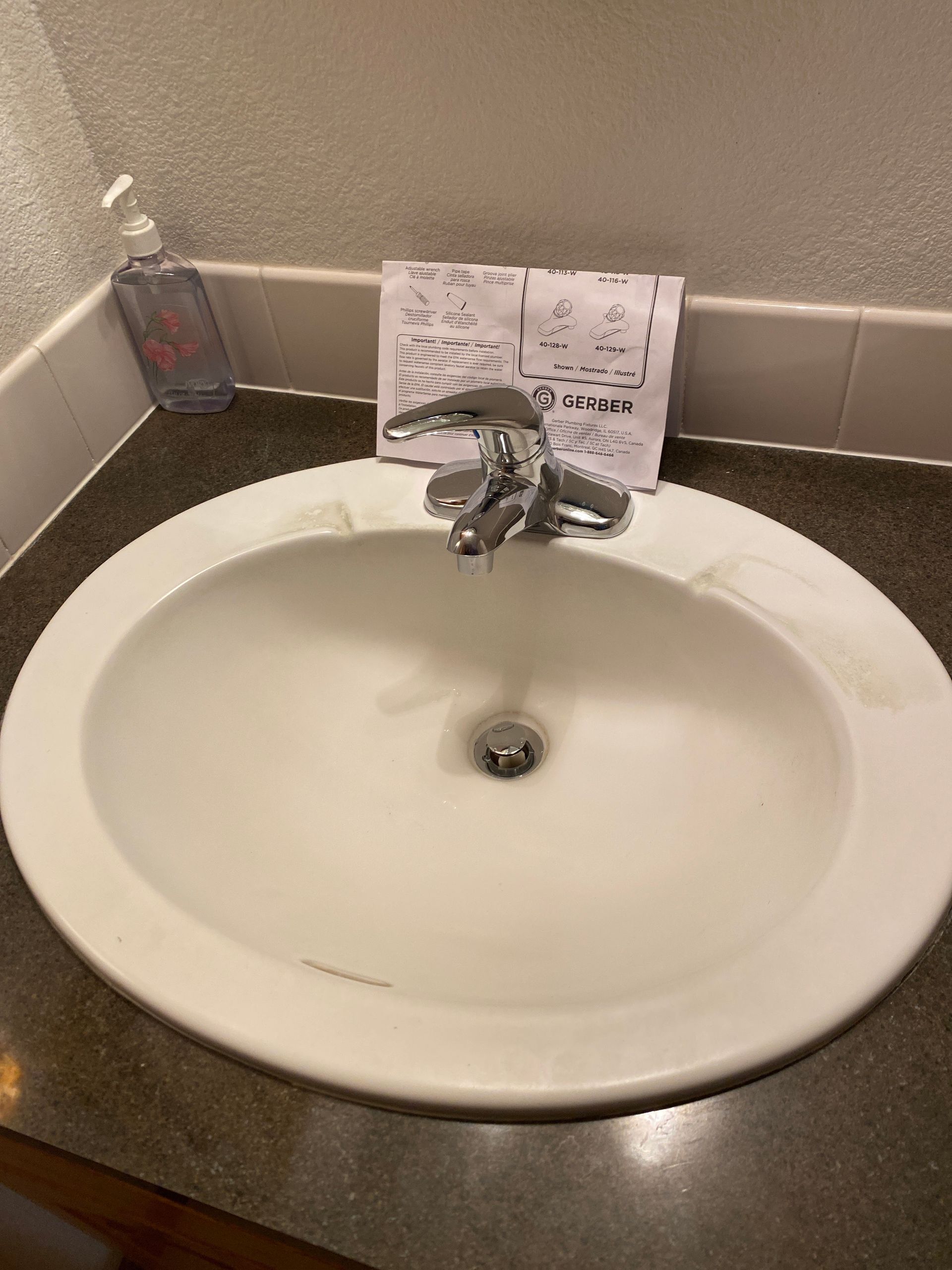 A bathroom sink with a soap dispenser on the counter.